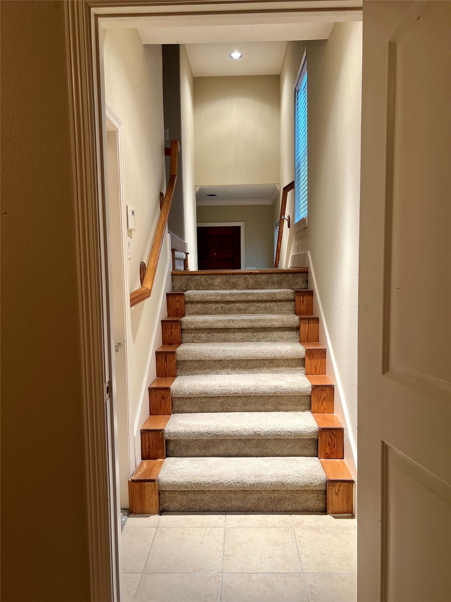 1625 Cohn Street, Houston, TX 77007 This photo shows a well-lit, carpeted staircase with wooden accents, leading up to the second-floor living area. The neutral walls and windows provide a bright, welcoming atmosphere.