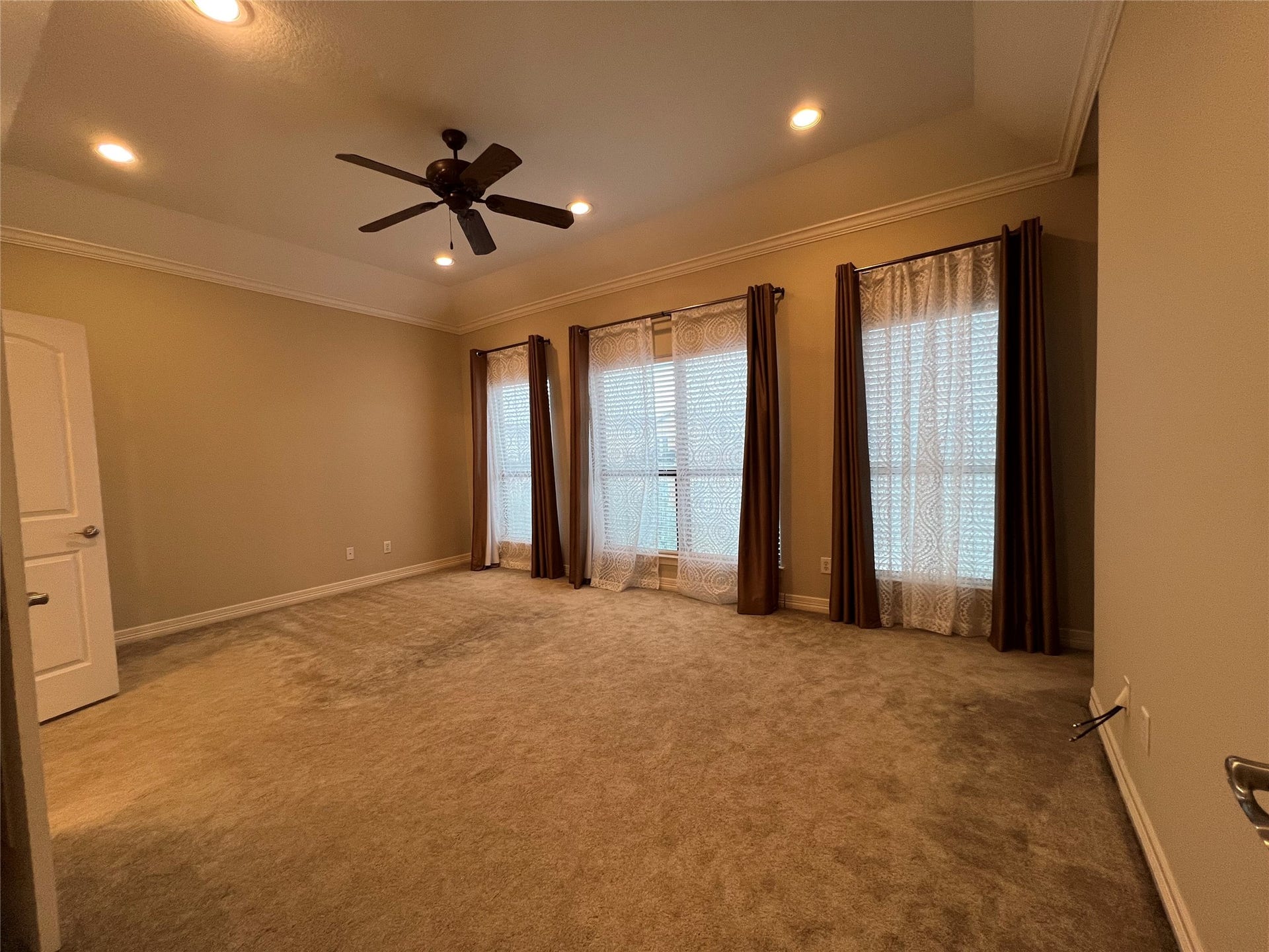 1625 Cohn Street, Houston, TX 77007 The master bedroom features neutral walls, plush carpeting, and large windows with curtains, allowing plenty of natural light. It includes recessed lighting and a ceiling fan, offering a comfortable and inviting atmosphere.