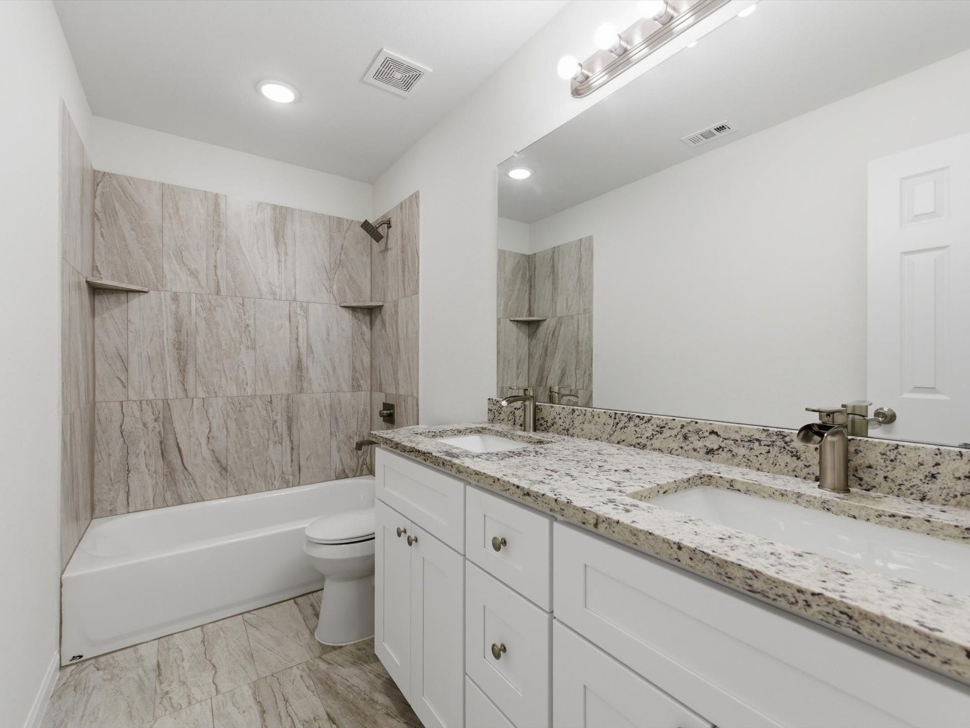 The secondary bathroom is designed with sleek finishes, granite counters, and dual sinks creating elevated everyday living.