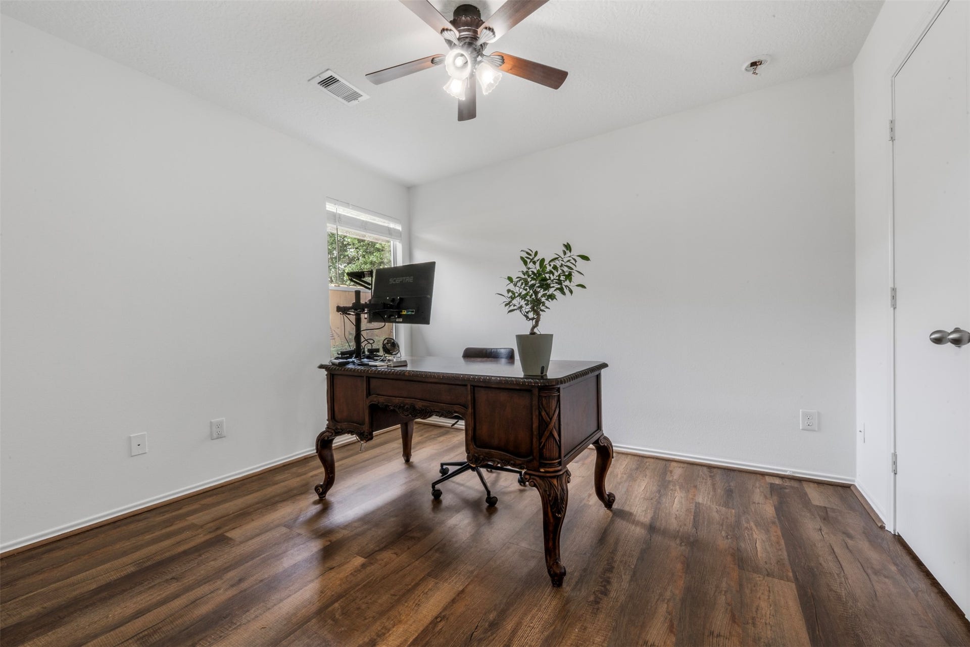 9750 Gulfstream Drive, Conroe, TX 77303 Work comfortably in this bright home office with wood flooring, a ceiling fan, and natural light, blending seamlessly with the homes consistent design throughout.