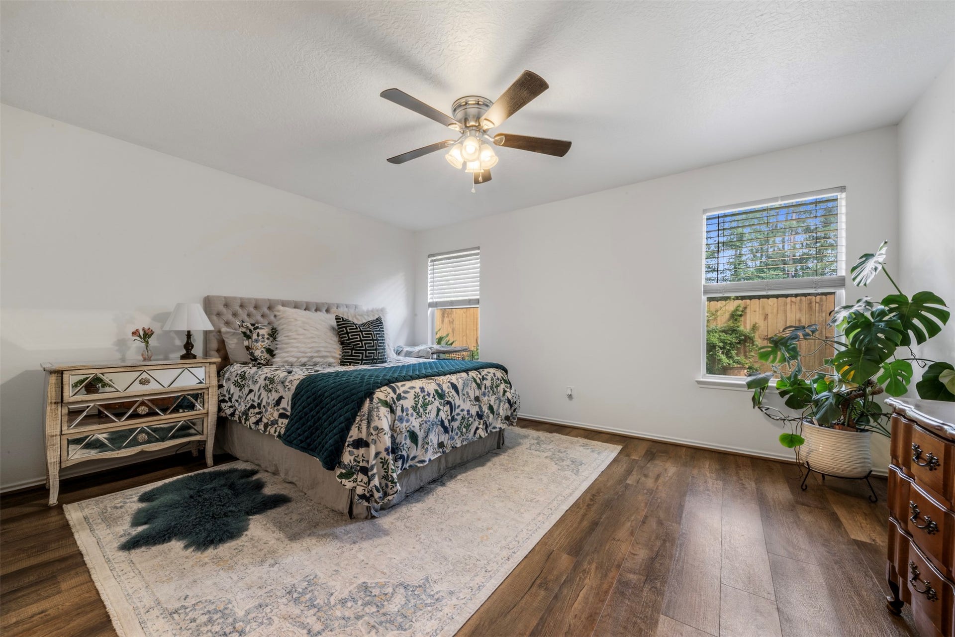 9750 Gulfstream Drive, Conroe, TX 77303 A warm and inviting bedroom with hardwood floors, a ceiling fan, and two windows that fill the space with natural light, offering a spacious and comfortable setting.