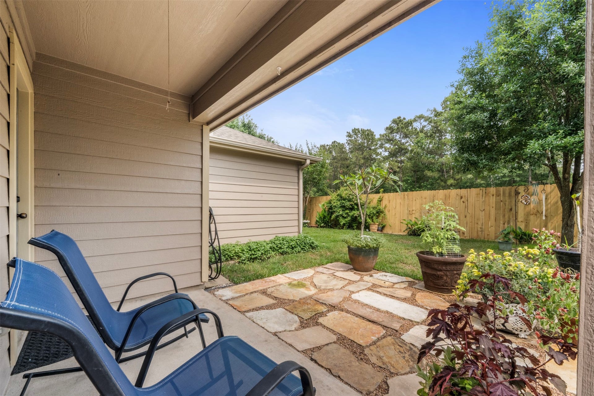 9750 Gulfstream Drive, Conroe, TX 77303 This covered patio with a stone pathway and surrounding greenery offers a peaceful, inviting setting perfect for unwinding.