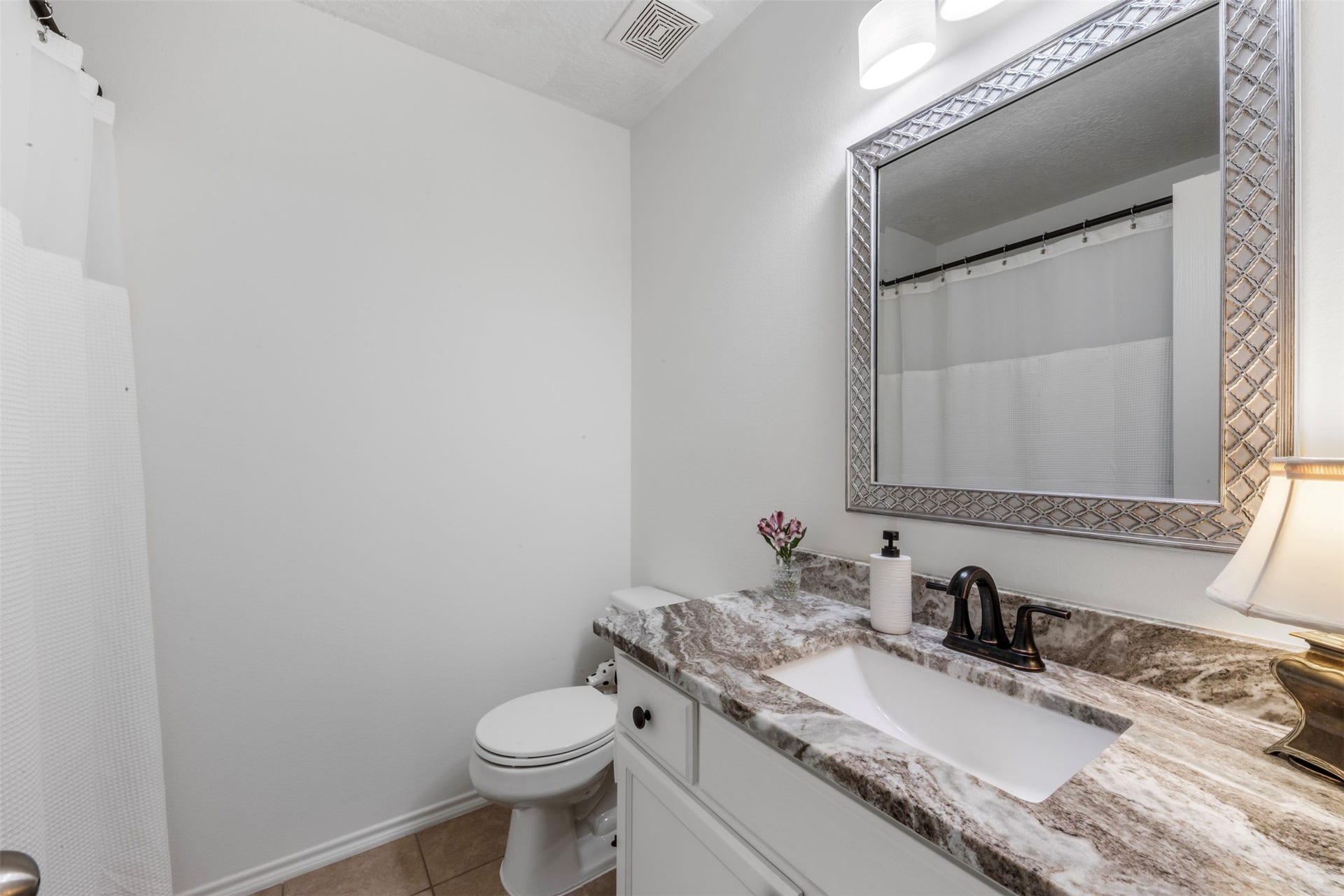 9750 Gulfstream Drive, Conroe, TX 77303 This bathroom features a clean, modern design with a marble countertop, an elegant framed mirror and white cabinetry. The neutral color palette creates a bright and inviting atmosphere.