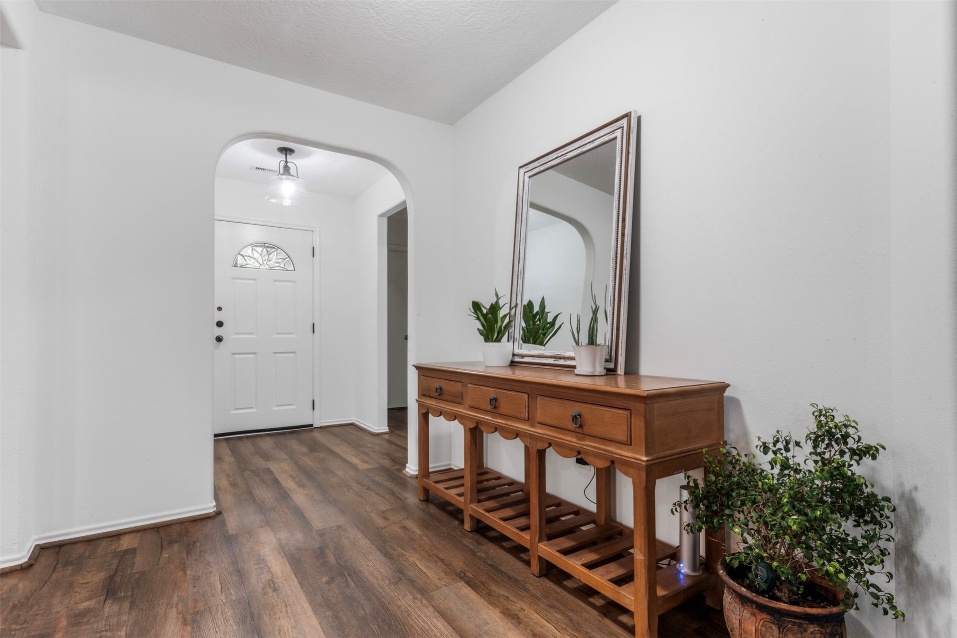 9750 Gulfstream Drive, Conroe, TX 77303 Welcoming entryway featuring a white front door, elegant archway and wood flooring, with space for a wooden console table that adds both charm and functionality.