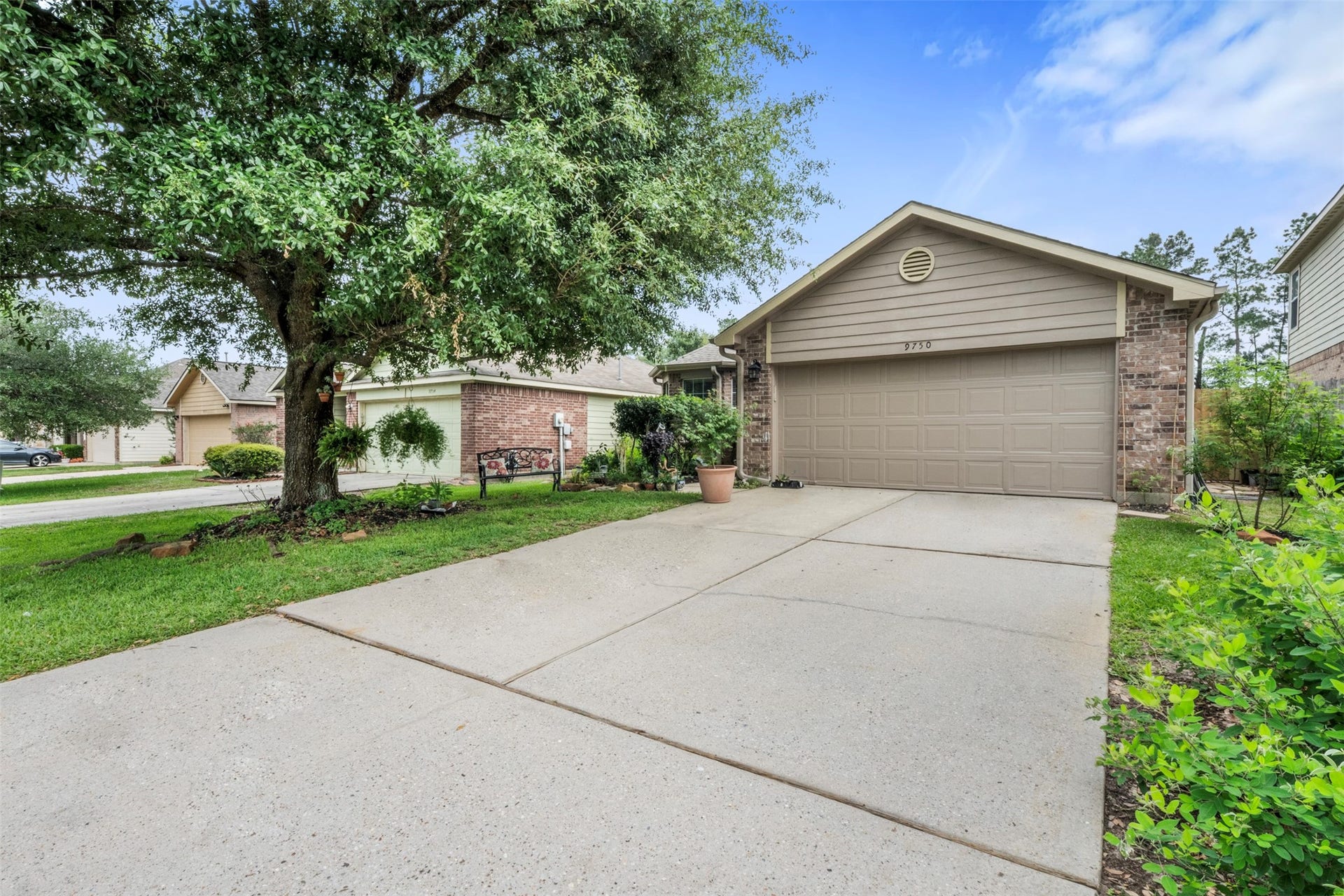 9750 Gulfstream Drive, Conroe, TX 77303 This photo showcases a charming single-story brick home with a well-maintained front yard, a spacious driveway leading to a two-car garage, and mature trees providing shade.