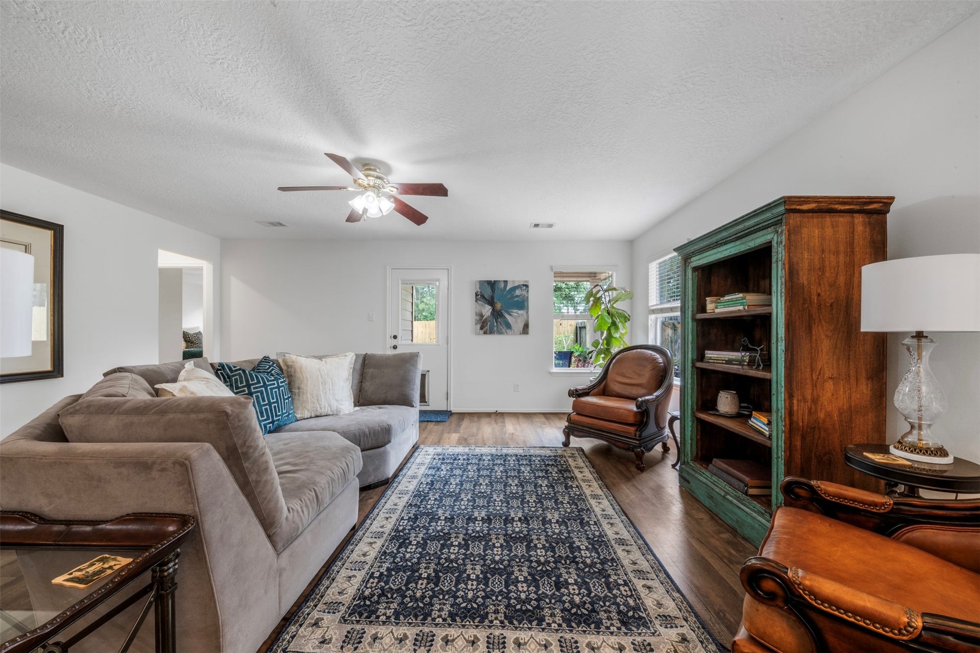 9750 Gulfstream Drive, Conroe, TX 77303 This bright, inviting living room offers neutral tones, rich wood flooring, and a ceiling fan, with abundant natural light enhancing the warmth of the space.