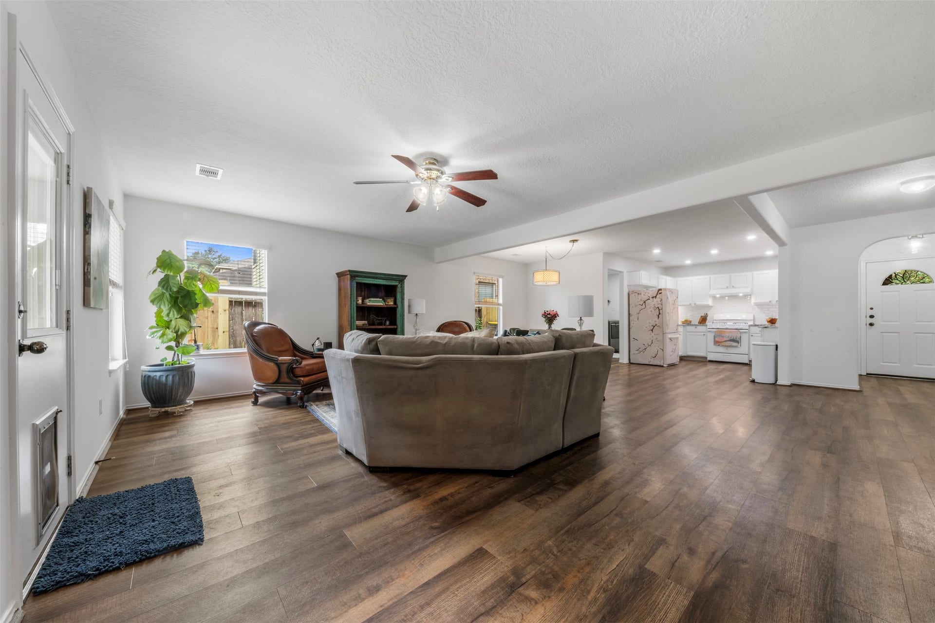 9750 Gulfstream Drive, Conroe, TX 77303 Another view of this inviting, open-concept living space with wood flooring and a ceiling fan, effortlessly connecting to the dining area and modern kitchen. Perfect for gatherings and relaxed living.