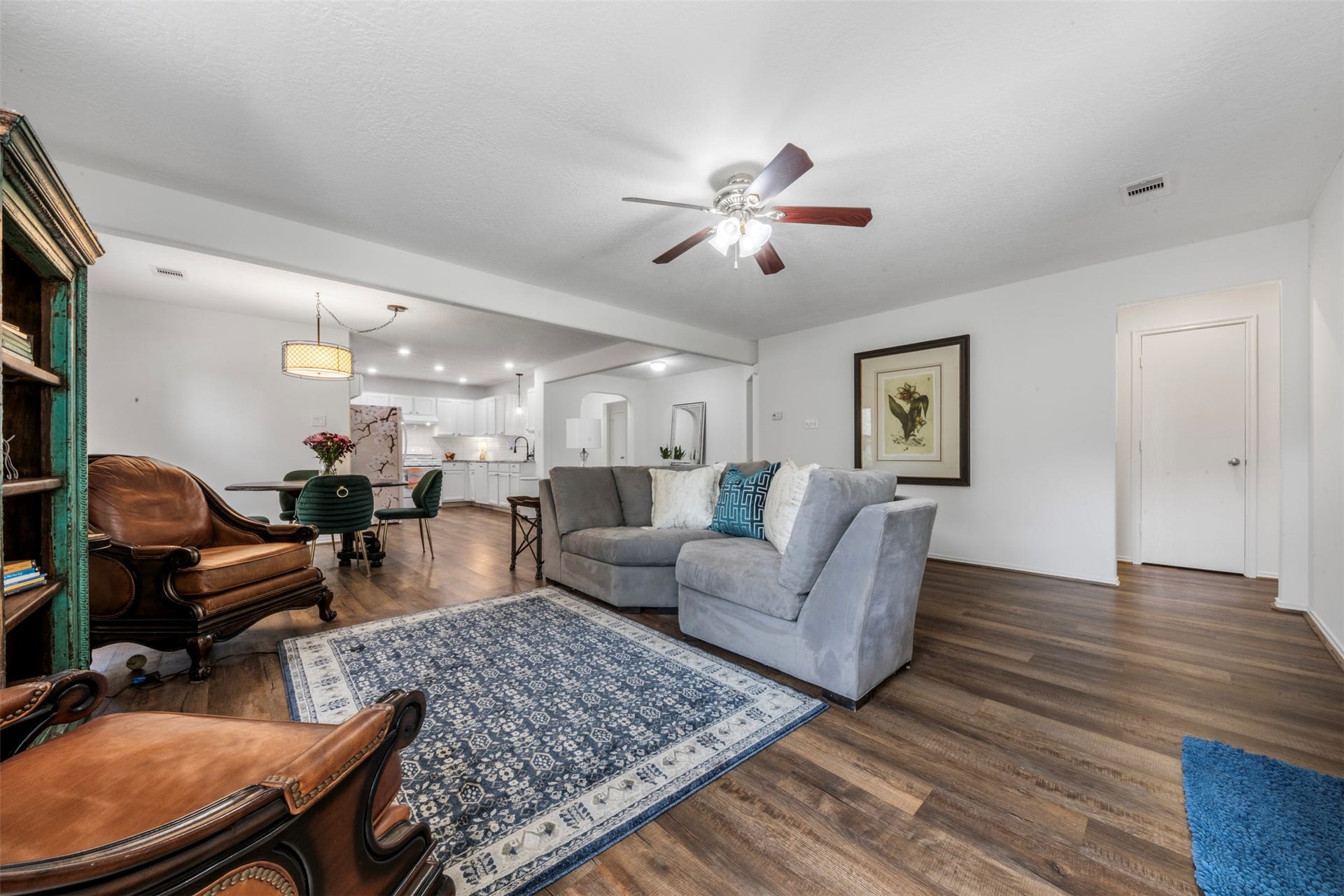 9750 Gulfstream Drive, Conroe, TX 77303 This inviting living space features an open layout with stylish wood flooring and a ceiling fan. It flows seamlessly into the dining area and modern kitchen, creating a welcoming environment for entertaining.