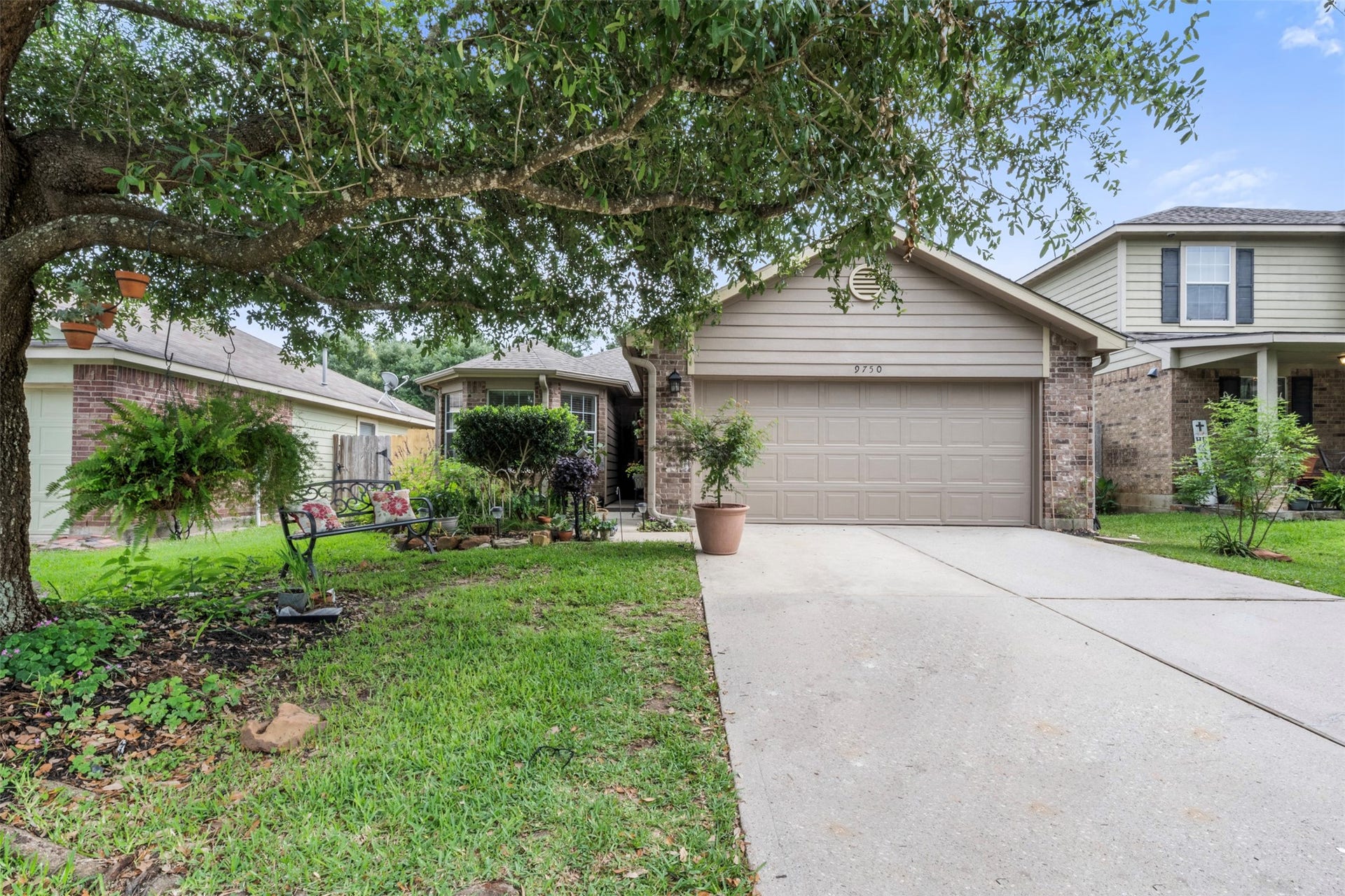 9750 Gulfstream Drive, Conroe, TX 77303 Charming single-story home with a two-car garage, nestled among lush greenery. A welcoming front yard and mature tree provide beautiful shade and inviting curb appeal.
