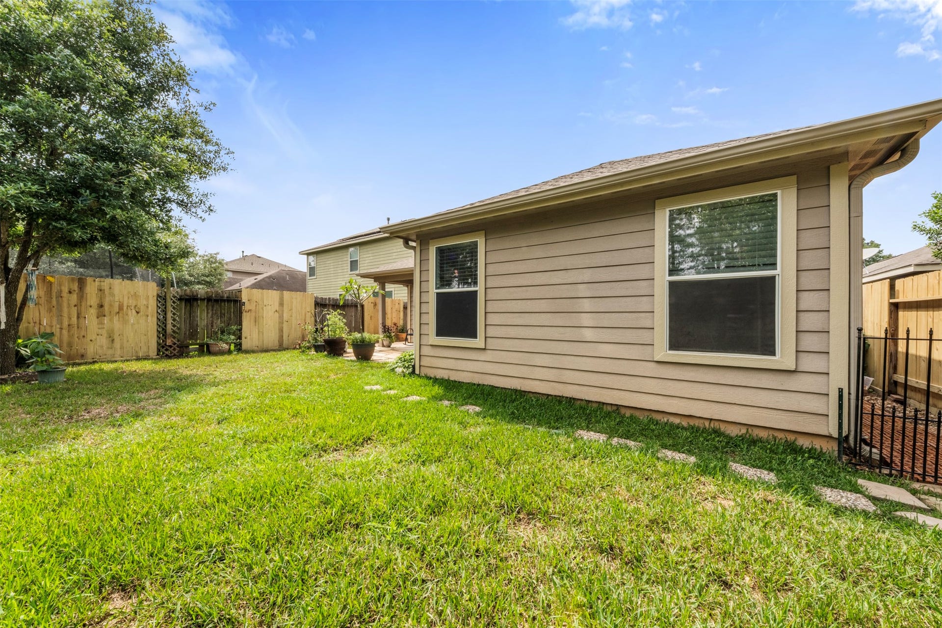 9750 Gulfstream Drive, Conroe, TX 77303 Expansive backyard offering ample lawn space and a wooden fence for privacy, ideal for entertaining or enjoying outdoor activities.