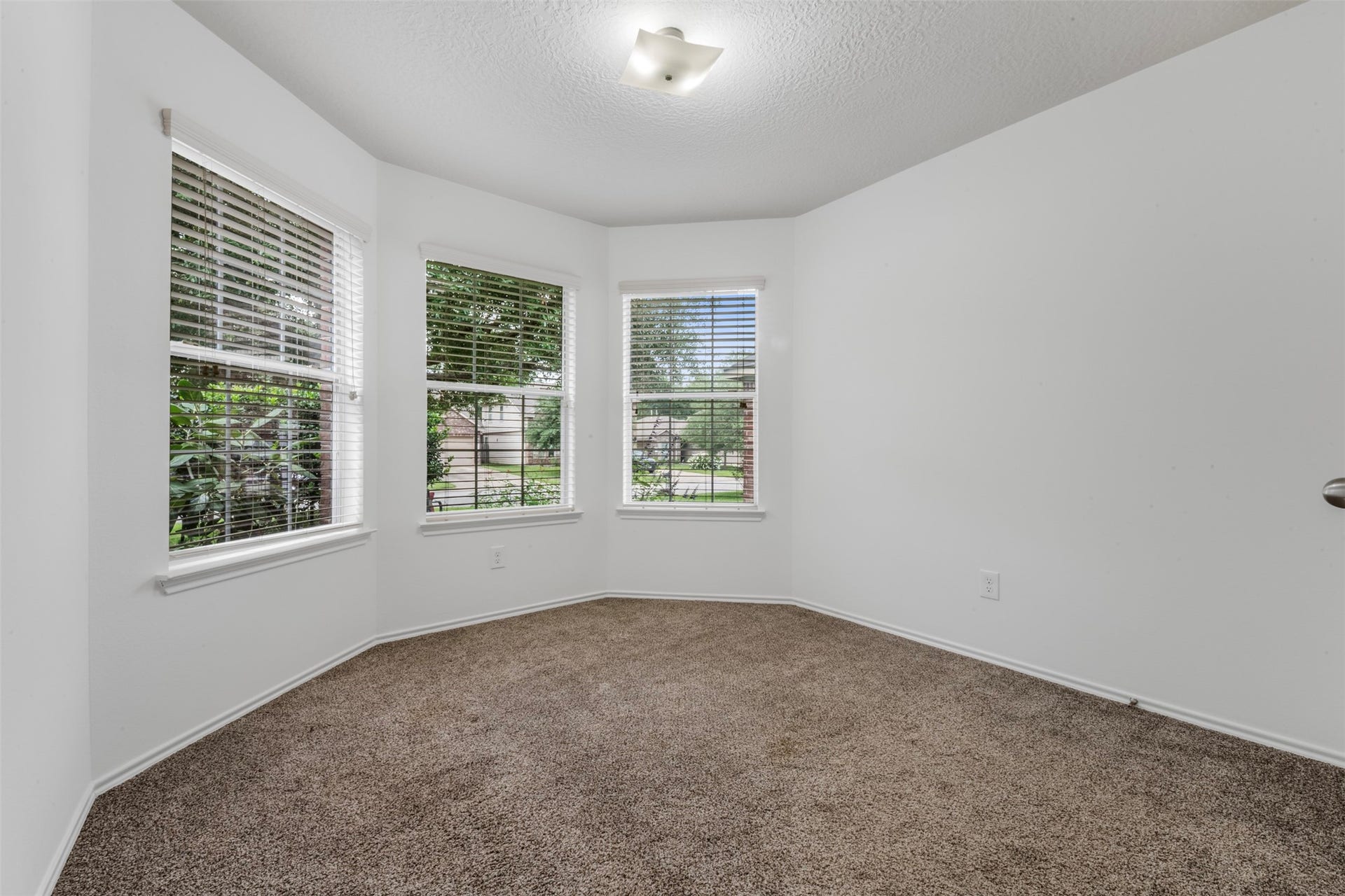 9750 Gulfstream Drive, Conroe, TX 77303 Bright and welcoming room with neutral carpeting, crisp white walls and three large windows with blinds, filling the space with natural light.