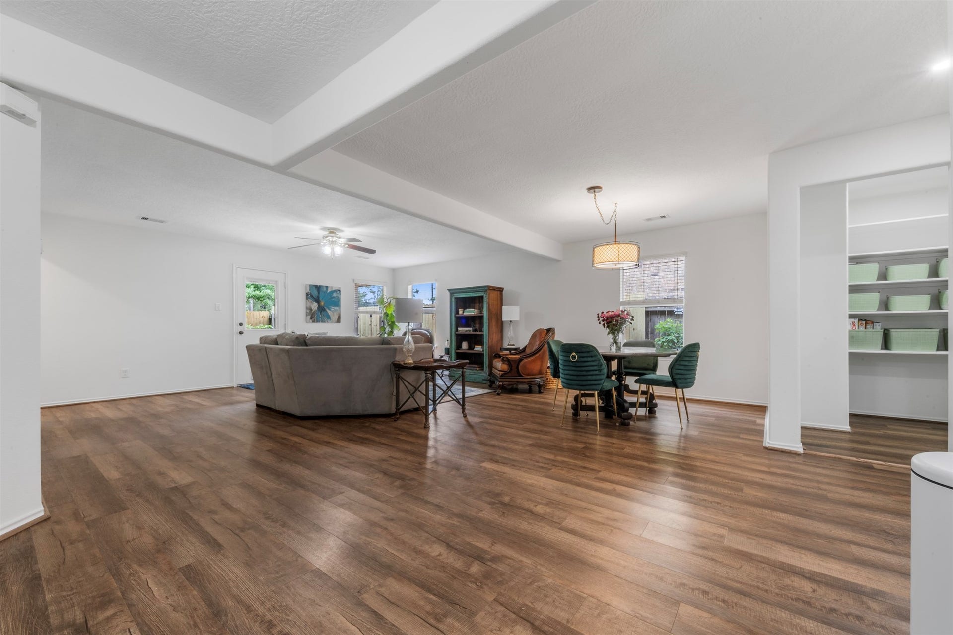 9750 Gulfstream Drive, Conroe, TX 77303 This spacious, open-concept living and dining area features warm wooden flooring, a cozy seating arrangement, and ample natural light. The room is accented with modern lighting fixtures and built-in shelving, creating a welcoming and functional space.