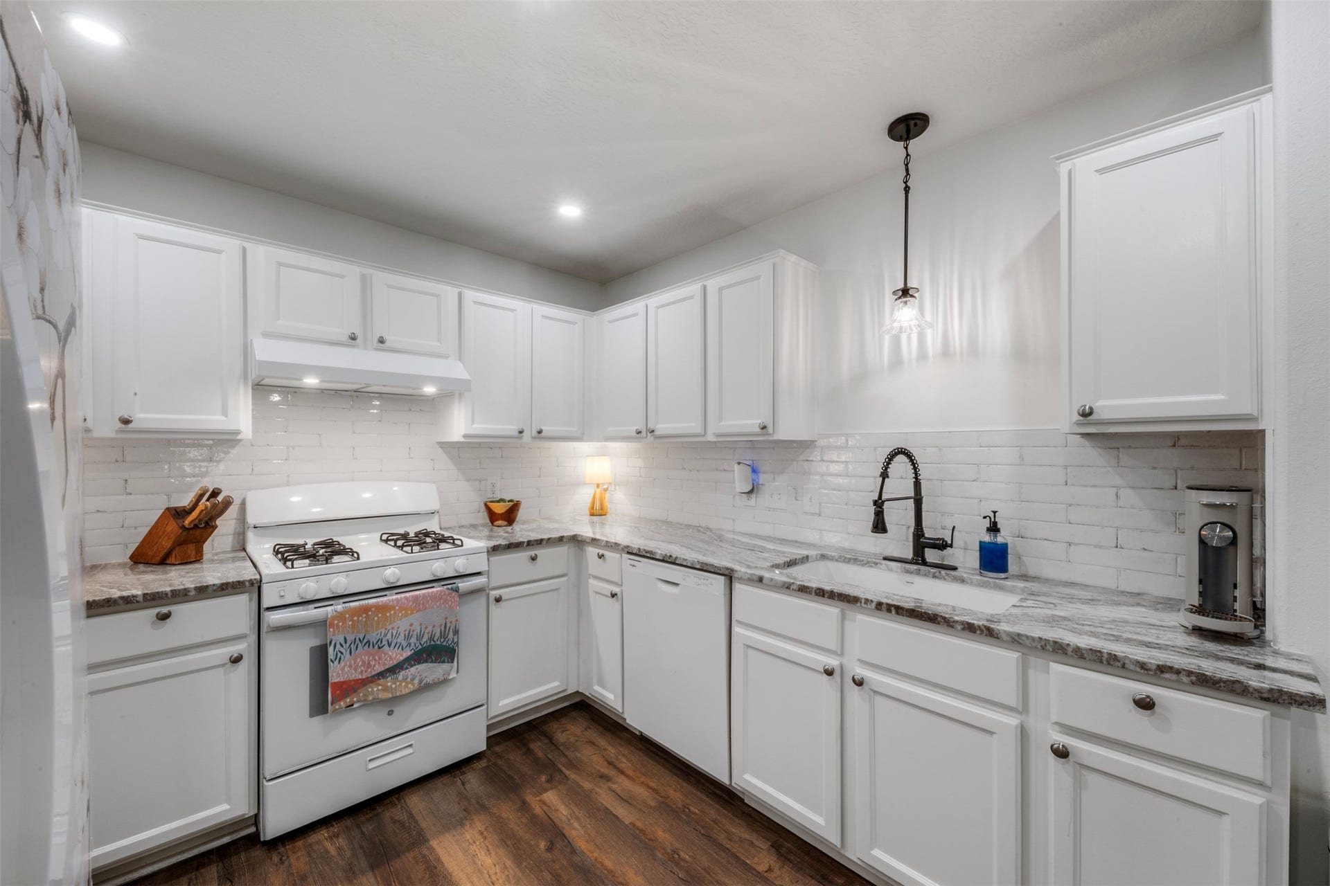9750 Gulfstream Drive, Conroe, TX 77303 This kitchen features white cabinetry, granite countertops, and a subway tile backsplash. It includes modern fixtures, creating a bright and inviting space.