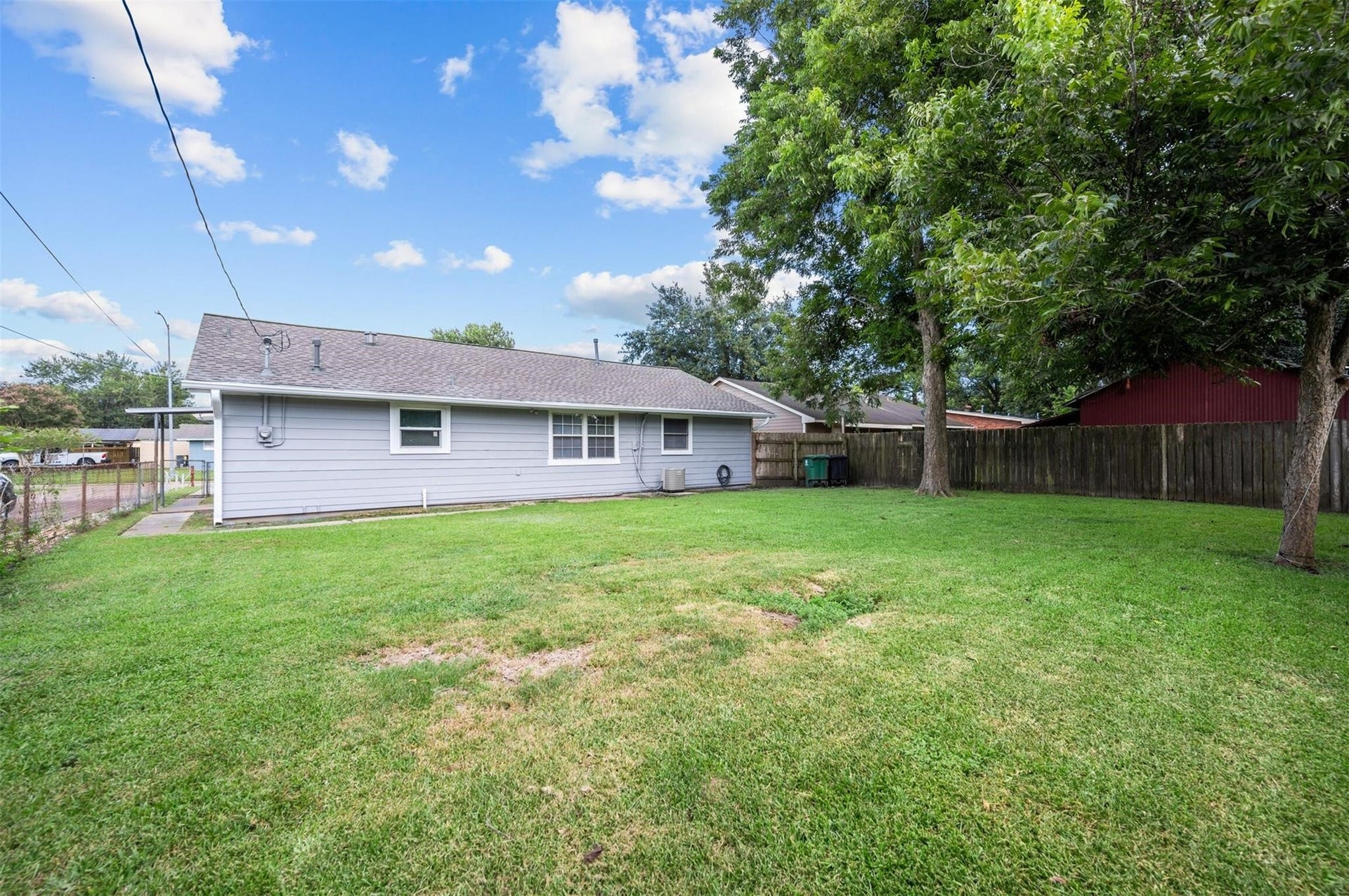 Spacious backyard with lush green lawn, mature trees, and a well-maintained fence offering privacy and room for outdoor activities.