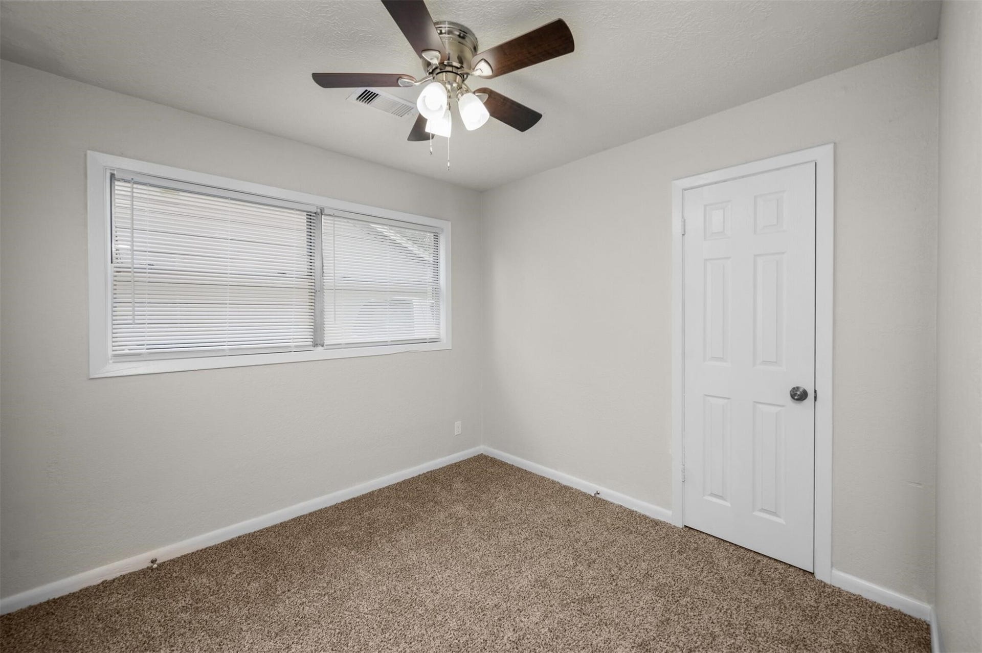 Bright and cozy room featuring a ceiling fan, neutral walls, and plush carpeting, perfect for a restful retreat.
