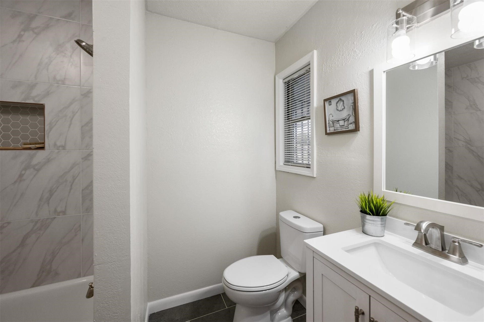 Modern bathroom featuring a sleek vanity, elegant tilework in the shower, and ample natural light.