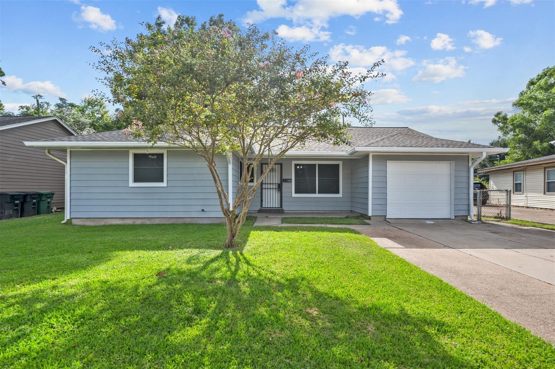 Charming single-story home with a fresh exterior, featuring a neatly manicured lawn, a welcoming front porch, and a one-car garage.