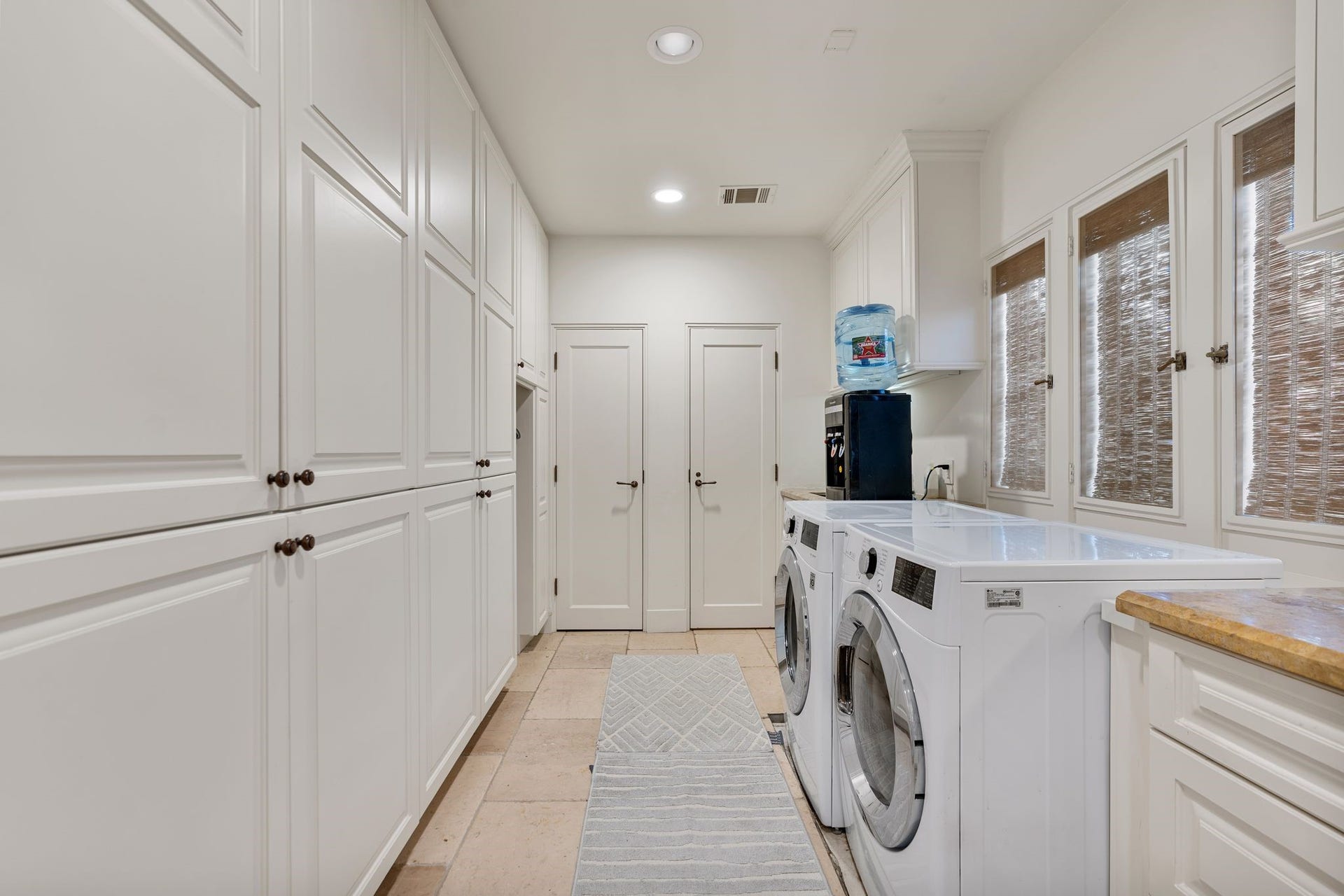 [Laundry / Utility Room]
Positioned in a short hall that leads from the kitchen to a driveway entrance. Abundant cabinet and closet storage. Sink (not visible) is at right.