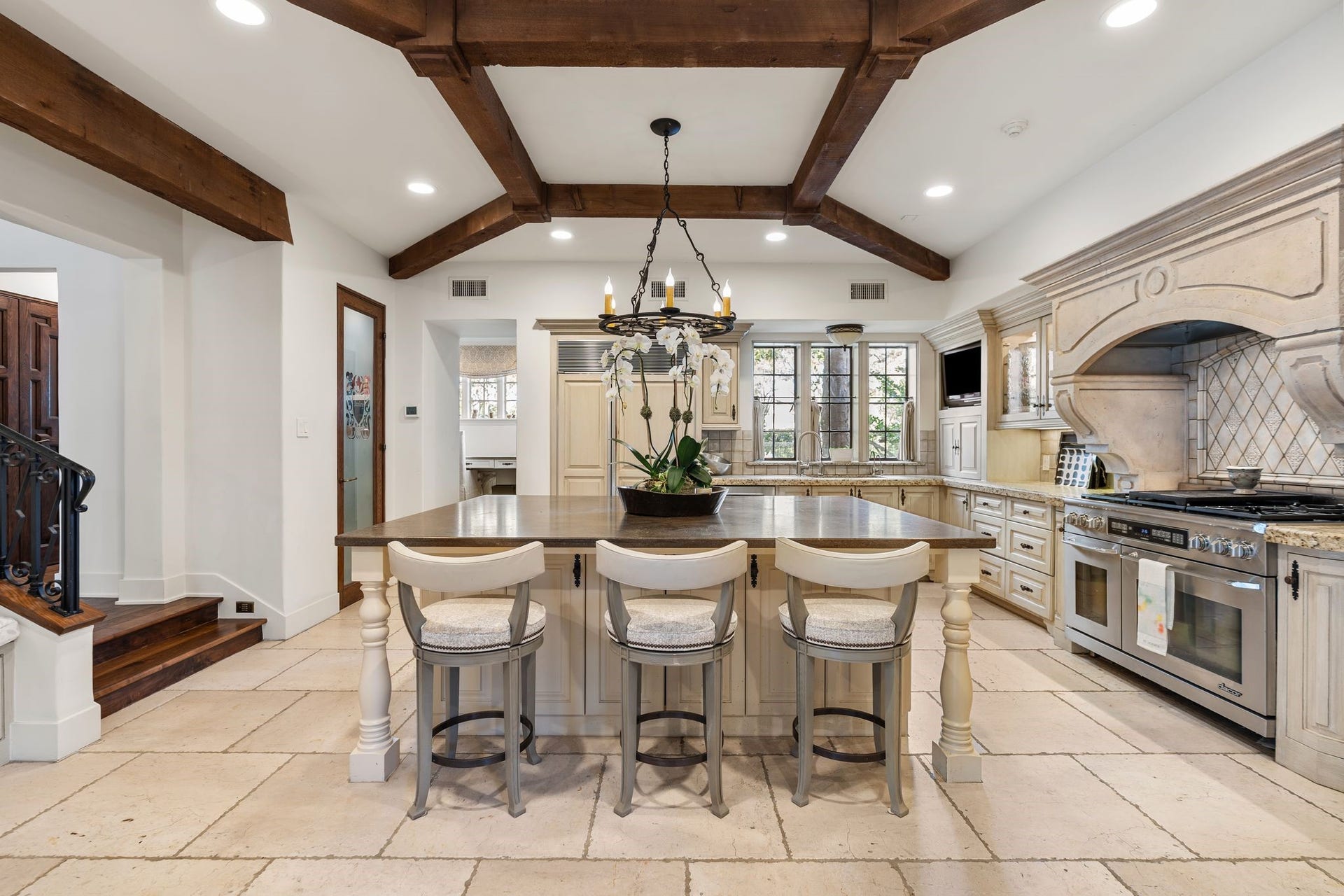 [Kitchen]
An alternate view of the kitchen reveals the beamed ceiling, opaque glass door to the pantry, and appliance garage with television niche (right/rear).