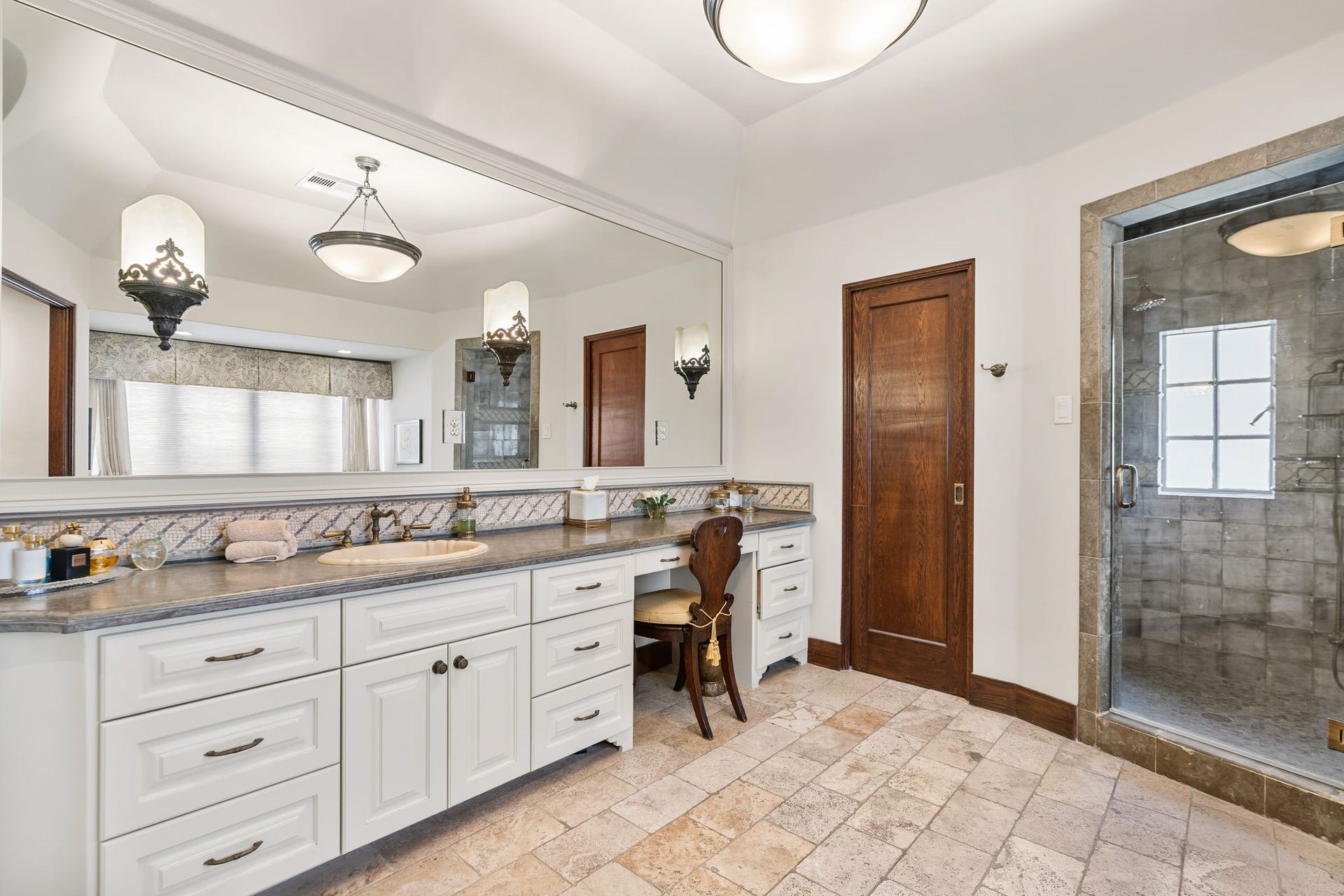 [Primary Bath #2]
Sink and vanity cabinets have a stone deck, custom tiled backsplash, and a mirrored wall with sconces.