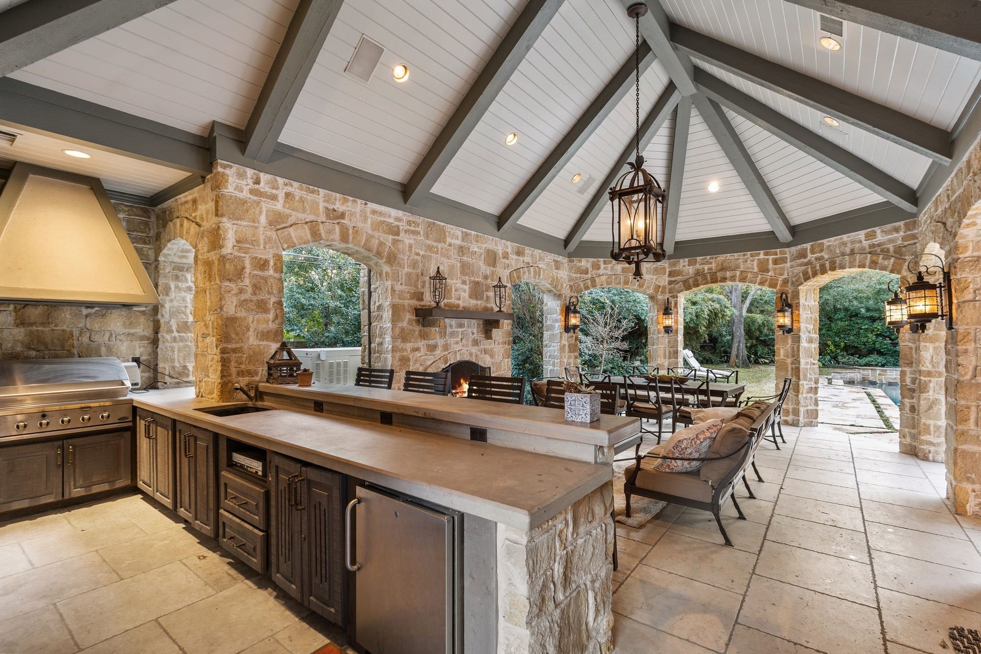[Pavilion]
Spacious open gathering and dining spaces enhance the pavilion. Note open brick arches, raised fireplace, stone serving ledge and countertops, under-counter refrigerator, deep sink, and DCS grill.