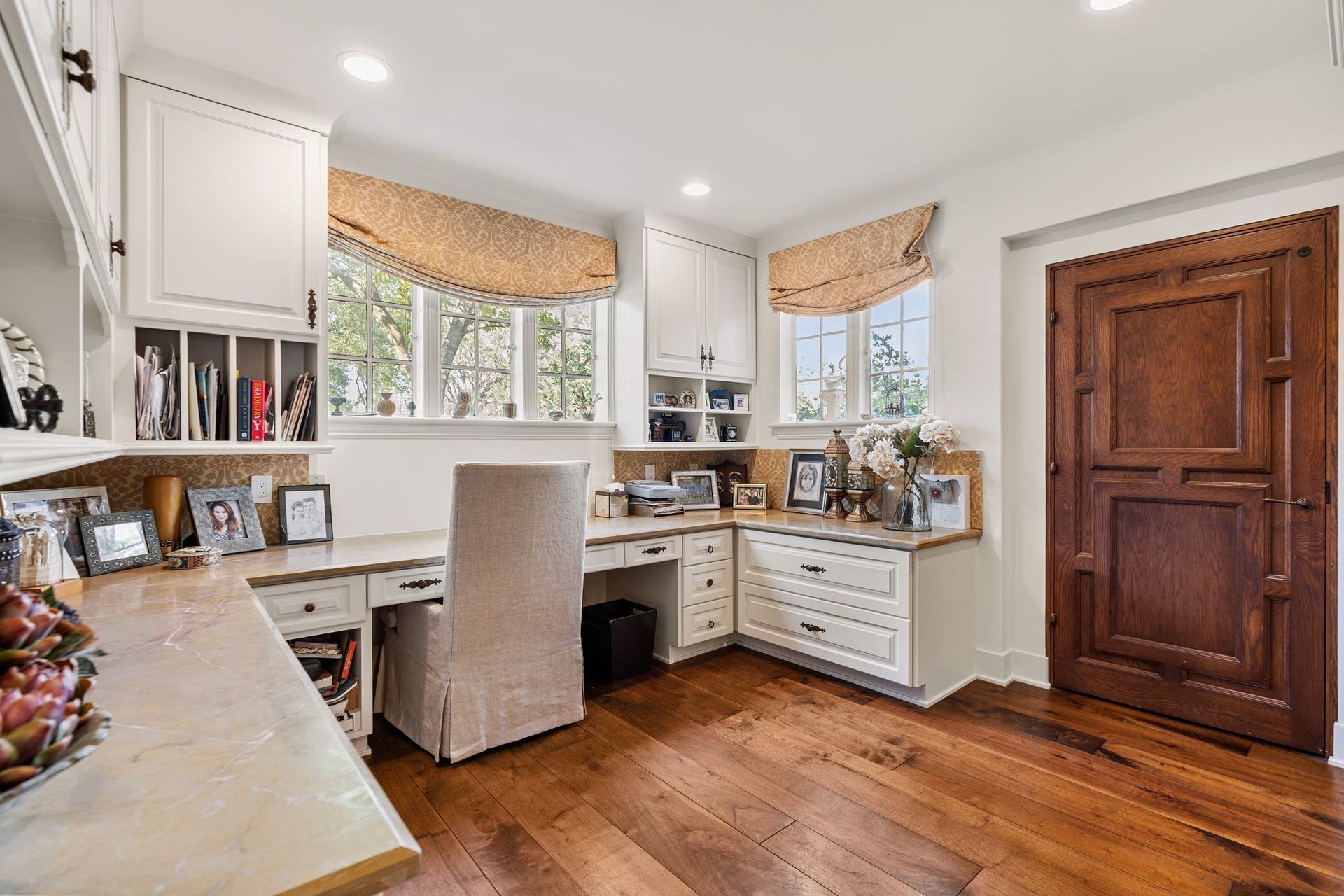 [Office]
Positioned beside the kitchen, the office overlooks the front gardens. Note wrap-around desk and abundant upper and lower storage. Paneled door (right) opens to the elevator.