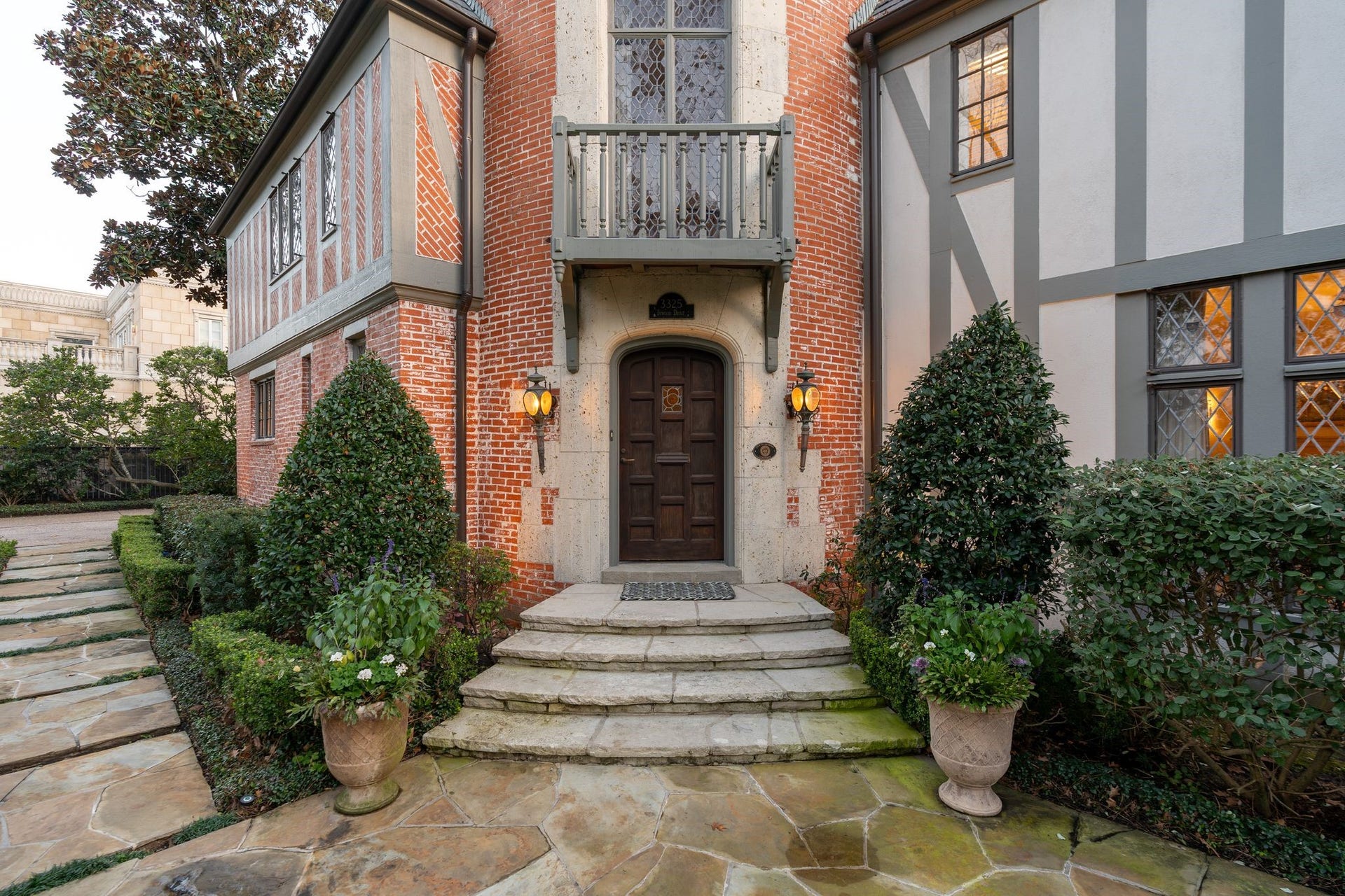 [Front Door]
A closer view of the front door reveals the arched door with Tudor Revival paneling, a stained and leaded bottle-glass panel, and arched, leaded glass window above the front door.