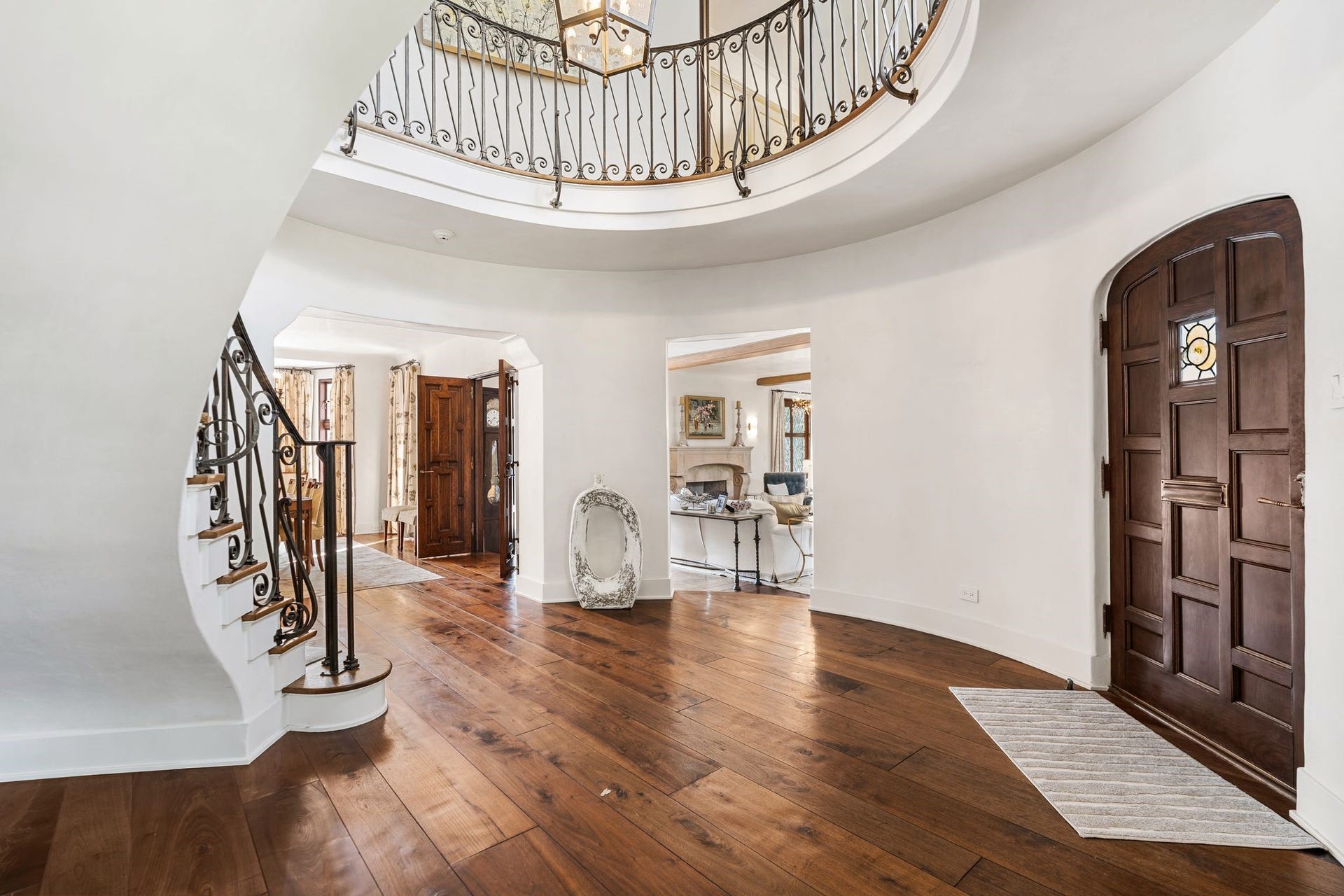 [Entry Hall]
The rotunda foyer features open doorways into the principal rooms. Dining room is at left-center, living room is at right-center. Note tightly-curved staircase with original, custom-fabricated iron balustrade. Replacement, wide plank hardwood floors extend through the first floor.