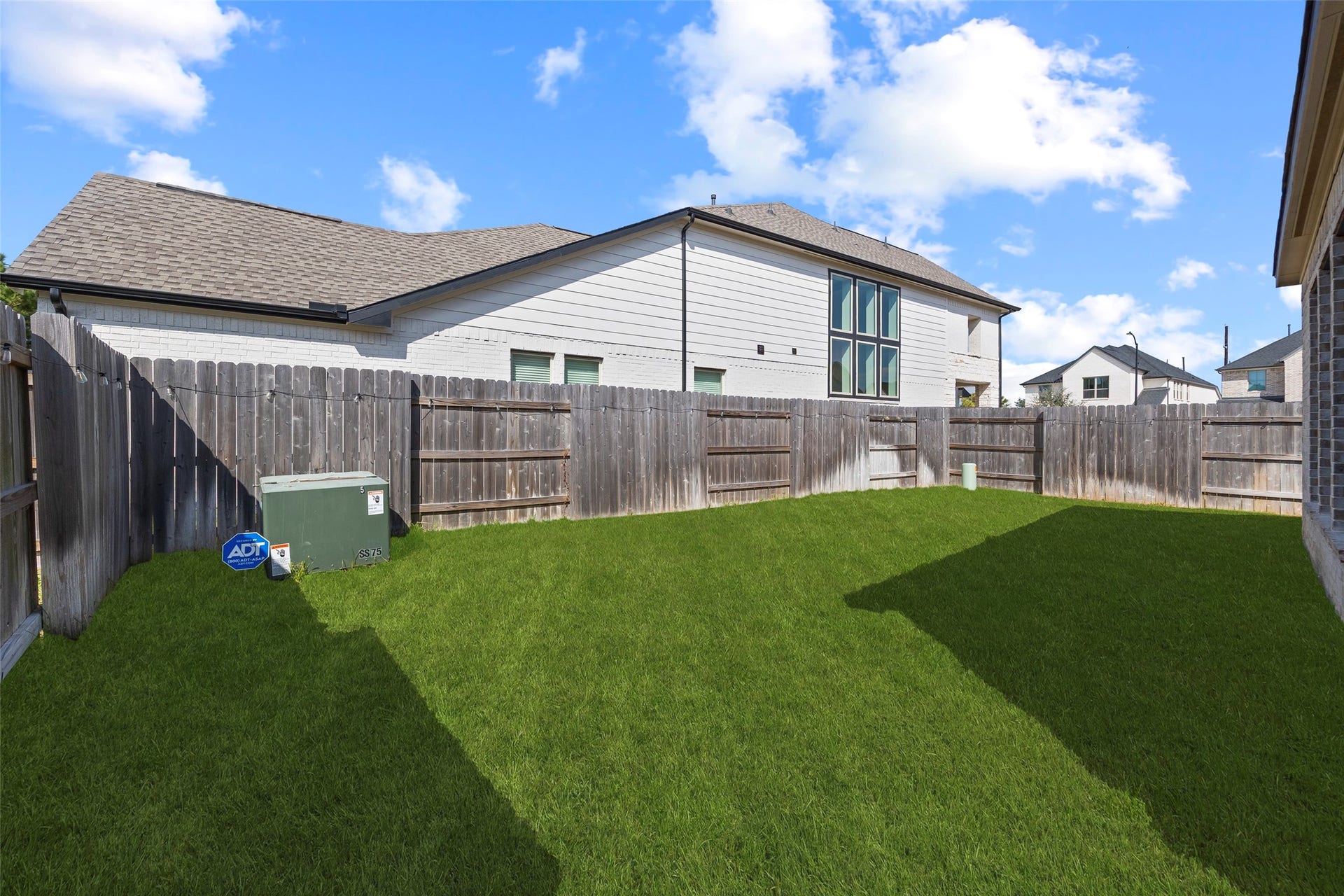 7311 Winding Aster Way, Katy, TX 77493 The backyard features an open stretch of lawn enclosed by wood privacy fencing. The grassy area offers flexibility for outdoor activities, garden beds or an additional seating arrangement. This view from near the covered patio shows the yards layout and the space available to personalize the outdoor setting.
