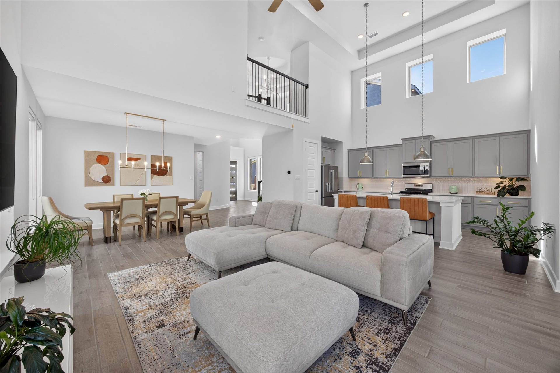 7311 Winding Aster Way, Katy, TX 77493 The family room, dining area and island kitchen share an open layout designed for gathering. Two levels of windows accentuate the high ceilings, while the upstairs railing adds architectural interest above. Continuous wood-look flooring connects the spaces and allows furniture to define each area.
