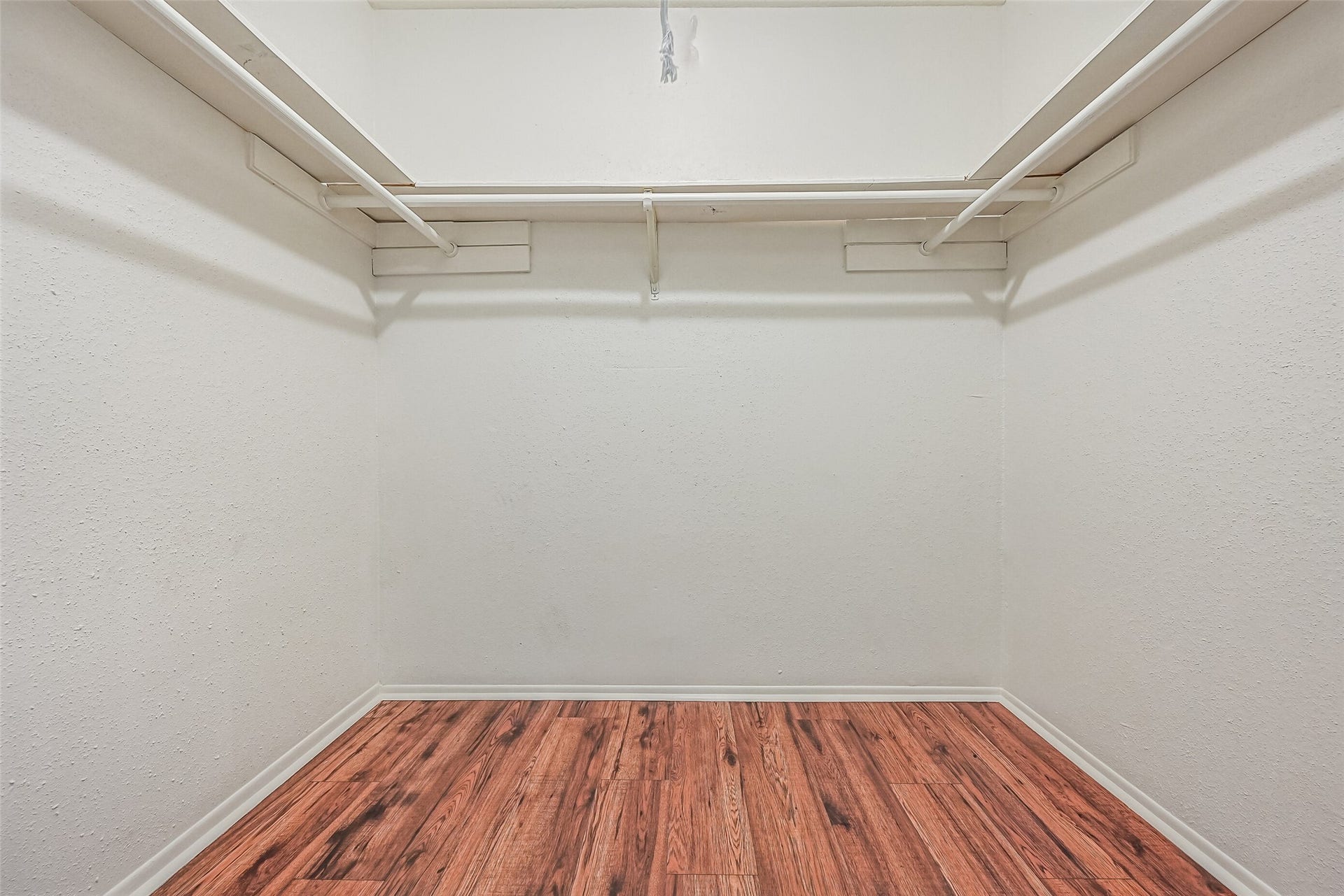 5005 Georgi Lane, #155, Houston, TX 77092 A generously sized walk-in closet provides excellent storage space in the primary suite! Hanging rods along both sides & the back wall offer plenty of room to organize clothing, while the wood-look flooring continues into the closet. There's also ample open floor space for additional storage solutions.