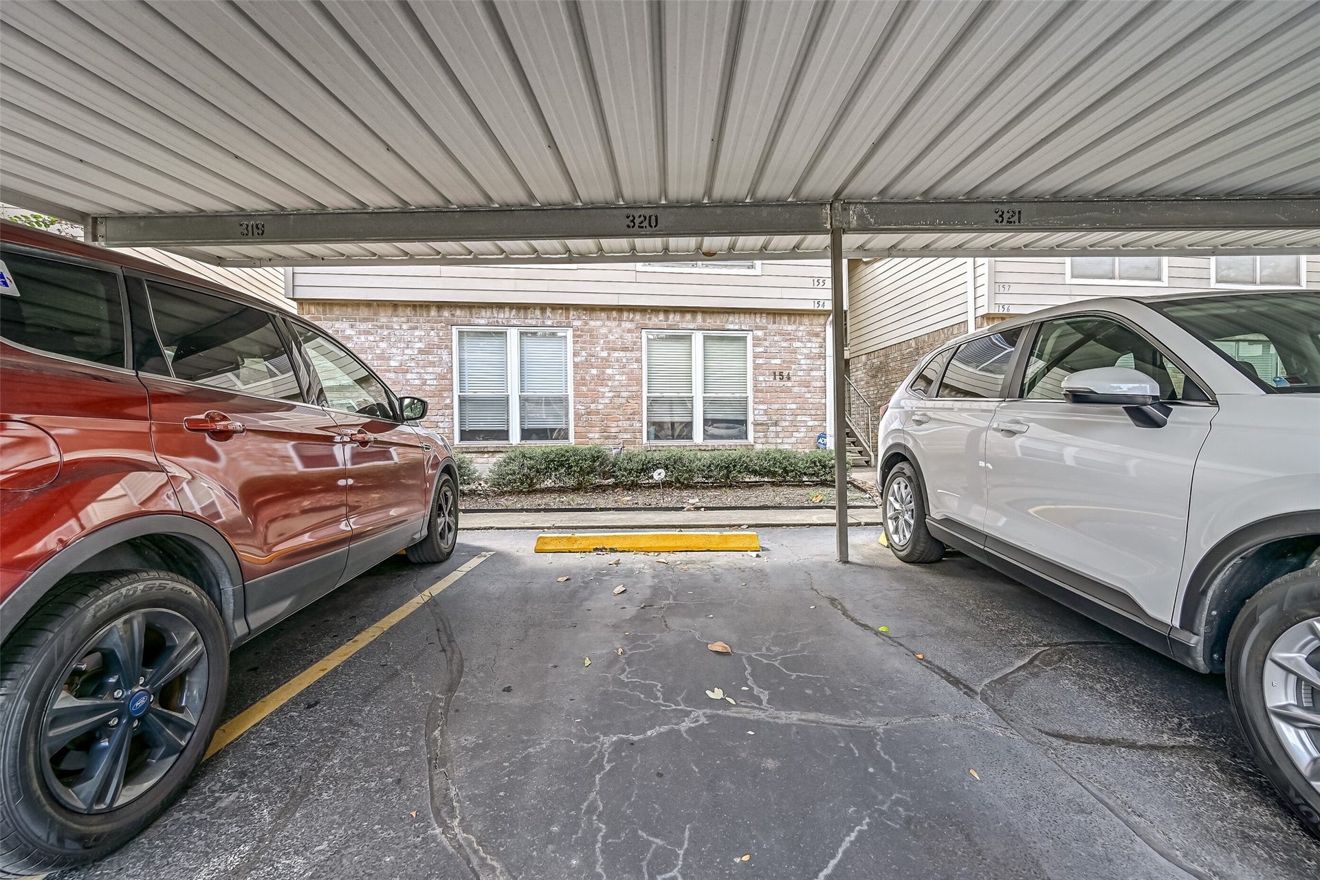 5005 Georgi Lane, #155, Houston, TX 77092 Covered parking provides protection from the elements, with parking space #320 pictured here. The covered parking area is located near the residential buildings, with sidewalks & stairway access to the second-floor units. An added benefit for residents of this Northwest Houston condominium community.