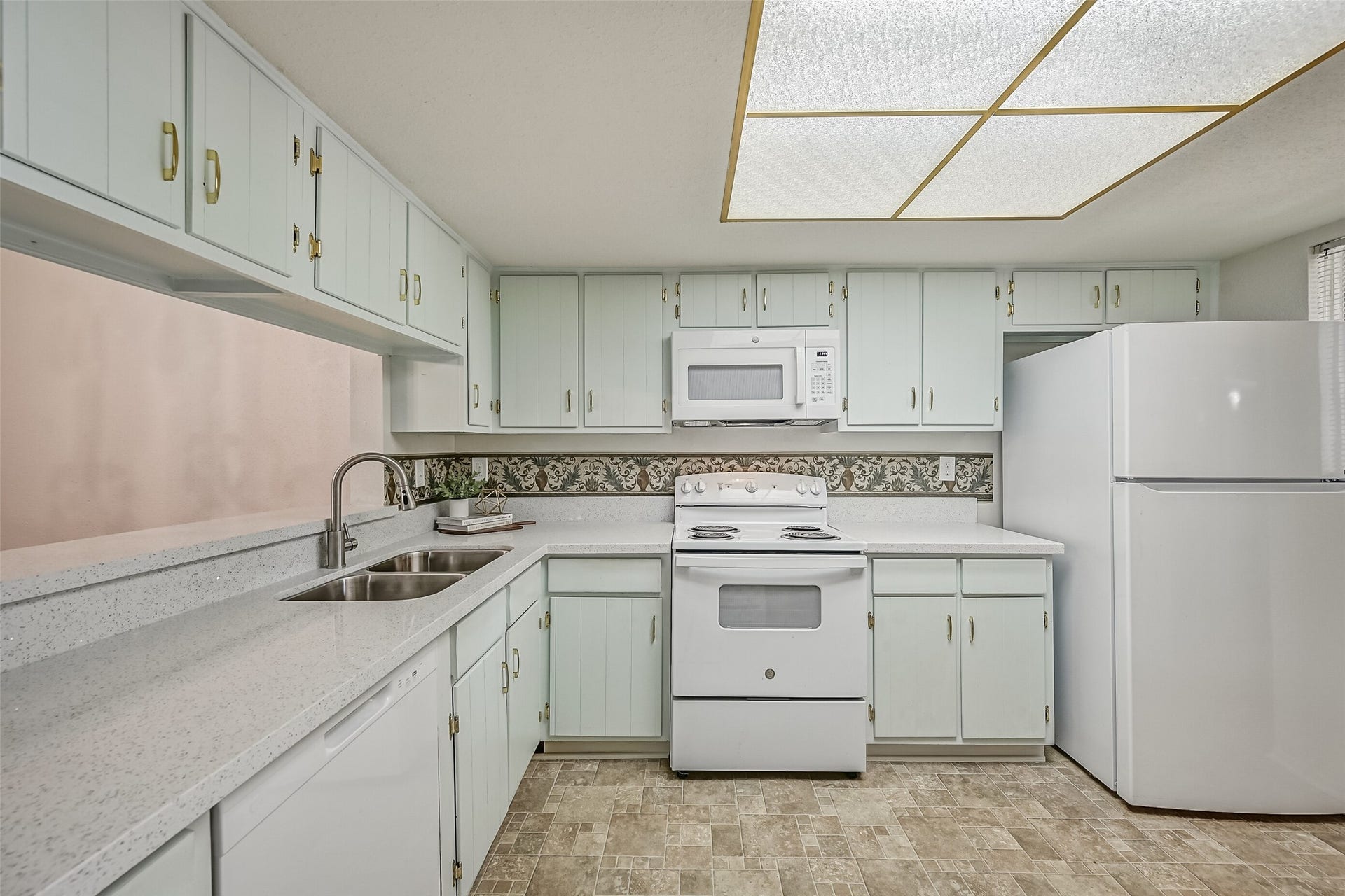 5005 Georgi Lane, #155, Houston, TX 77092 Another kitchen view showcases the extensive upper & lower cabinetry, white appliances & generous countertop space. Features include an electric range, built-in microwave, dishwasher, refrigerator & double-basin stainless steel sink with a gooseneck faucet. A decorative backsplash adds character.