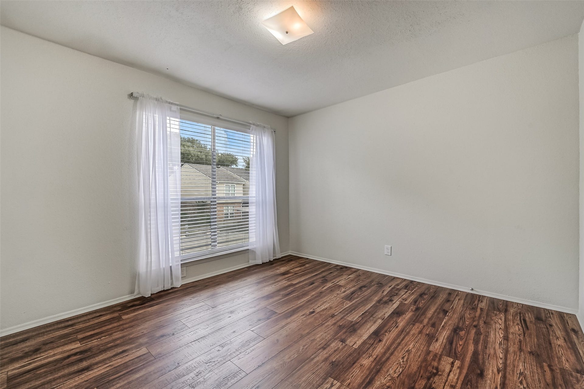 5005 Georgi Lane, #155, Houston, TX 77092 Natural light fills this inviting secondary bedroom through a large window with blinds & sheer curtains. The wood-look flooring continues into this room, complementing the neutral paint and providing a clean backdrop for your furnishings. A comfortable space to make your own!