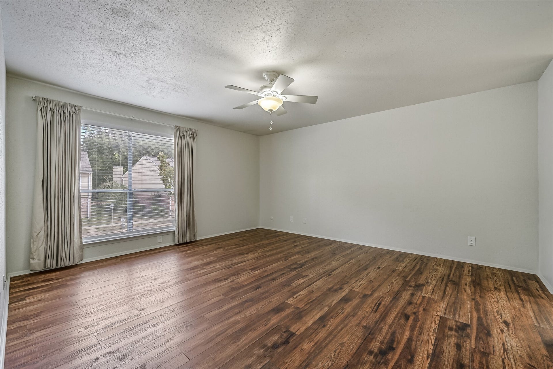 5005 Georgi Lane, #155, Houston, TX 77092 A large window with blinds & curtains brings natural light into the primary bedroom, while the wood-look flooring adds warmth to the neutral interior. With plenty of open wall space for furniture placement, this generously sized room offers flexibility for creating your ideal bedroom retreat.