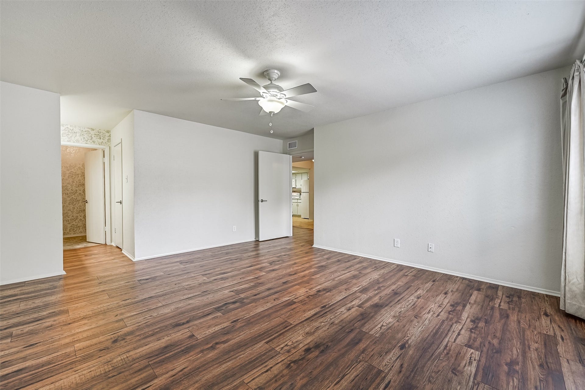 5005 Georgi Lane, #155, Houston, TX 77092 The spacious primary bedroom offers plenty of room for a king-sized bed & additional furnishings, with attractive wood-look flooring, neutral walls & a lighted ceiling fan. The generous floor plan includes access to a separate vanity area & bathroom, creating a comfortable primary suite.