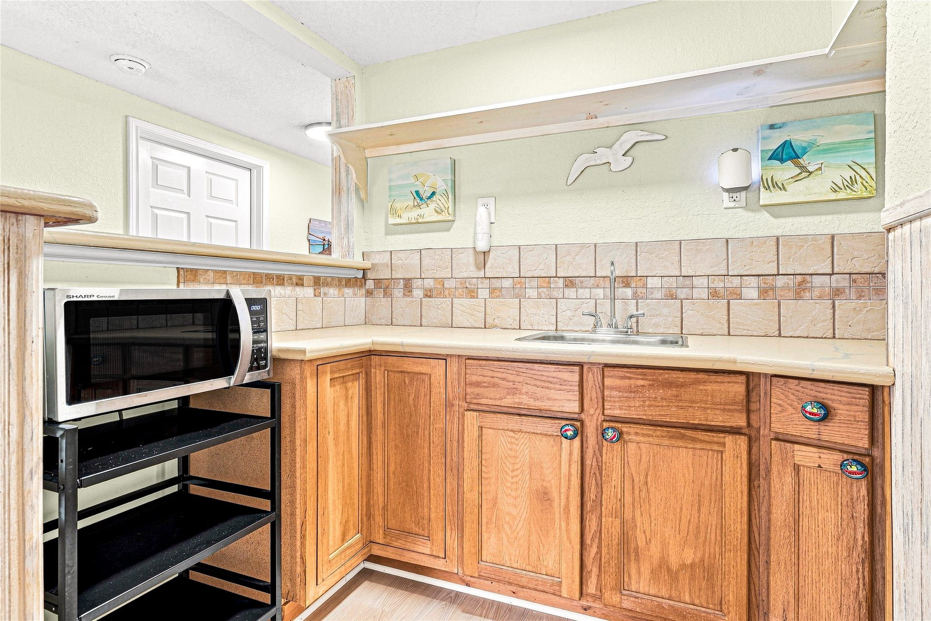 19 N Sandpiper Street, La Marque, TX 77568 Charming kitchenette with warm wood cabinets, decorative tile backsplash, and convenient countertop space, perfect for light meal prep or entertaining.