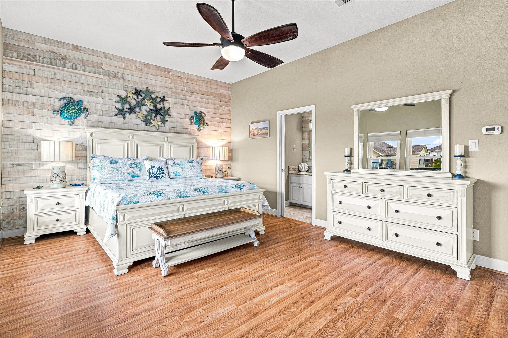 19 N Sandpiper Street, La Marque, TX 77568 Spacious bedroom featuring a coastal theme with a king-size bed, stylish wood accent wall, and elegant white furniture.