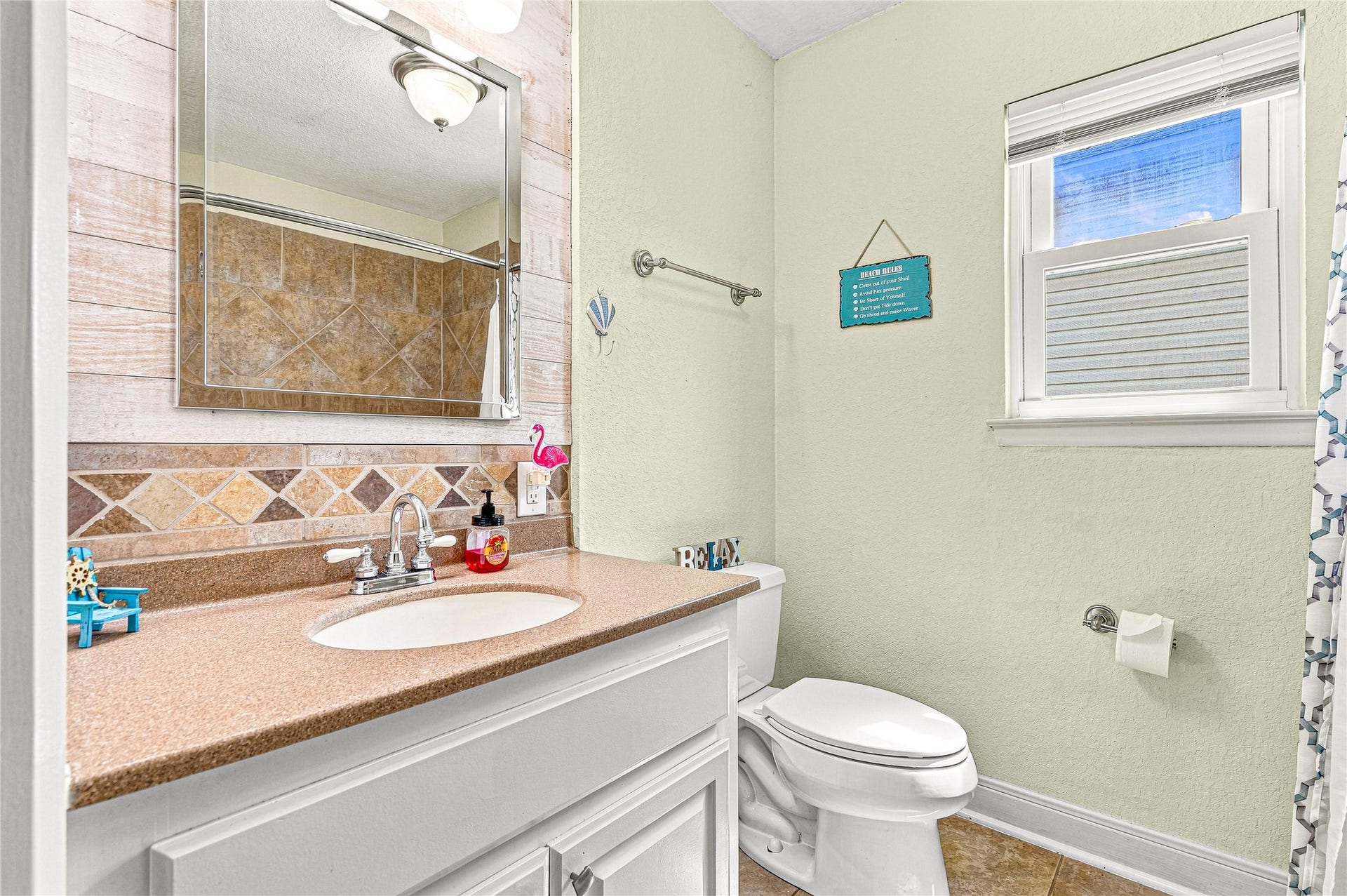 19 N Sandpiper Street, La Marque, TX 77568 Charming bathroom with a warm, neutral palette features a sleek countertop, stylish tiled backsplash, and a bright window for natural light.