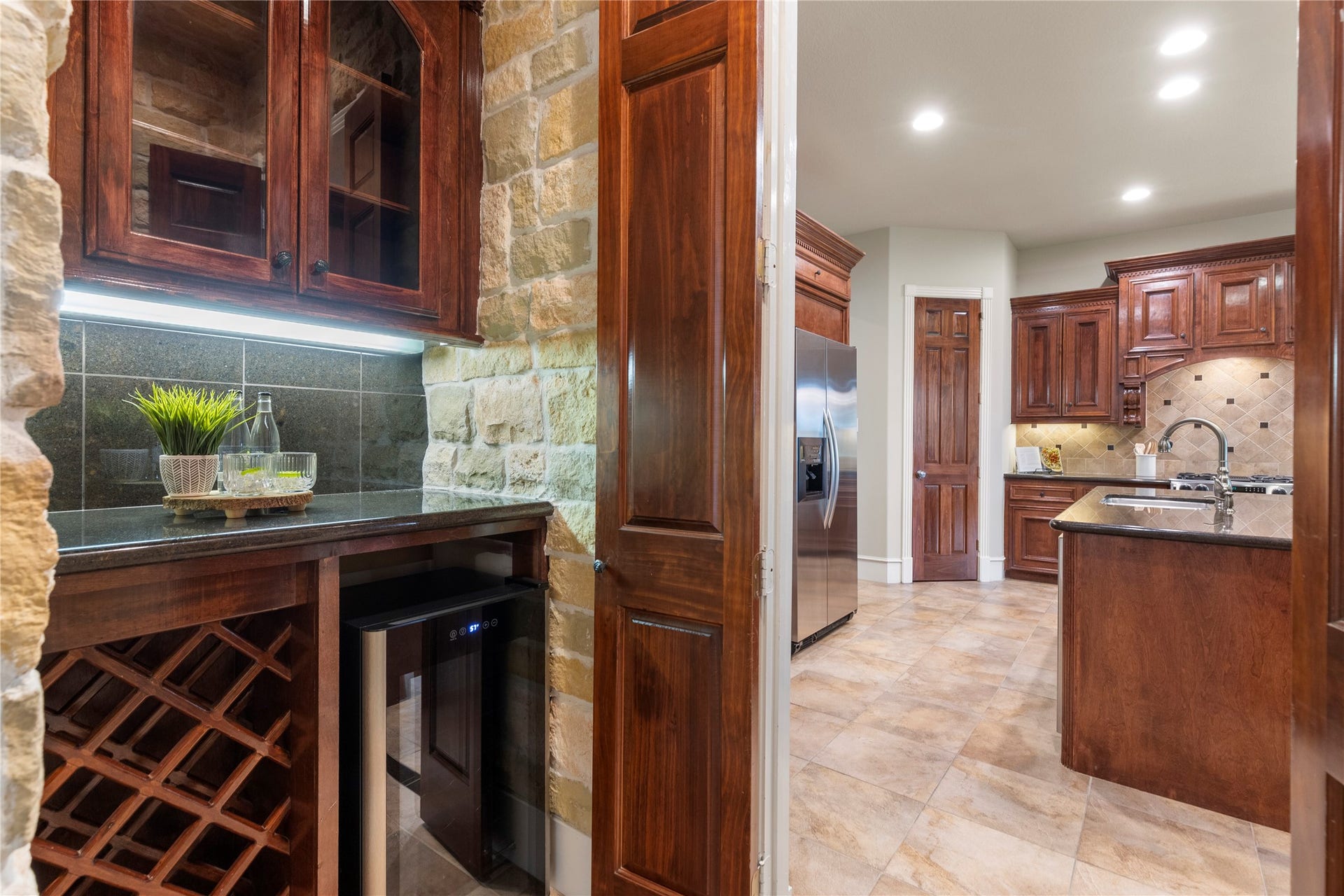6207 Windrose Hollow Lane, Spring, TX 77379 The wine pantry area includes rock accent walls and a 34 bottle wine refrigerator, adding a polished transition between kitchen and dining. It supports entertaining while giving the home another layer of custom detail.