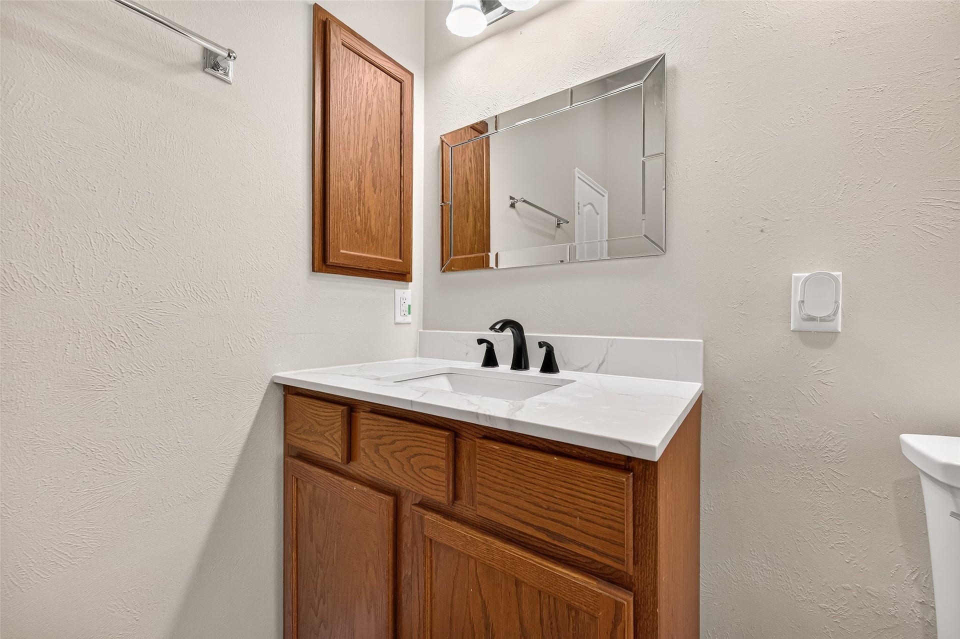 9307 Russeff Field Lane, Rosenberg, TX 77469 Bathroom vanity area featuring wood cabinetry, a countertop sink, and a wall-mounted mirror.
