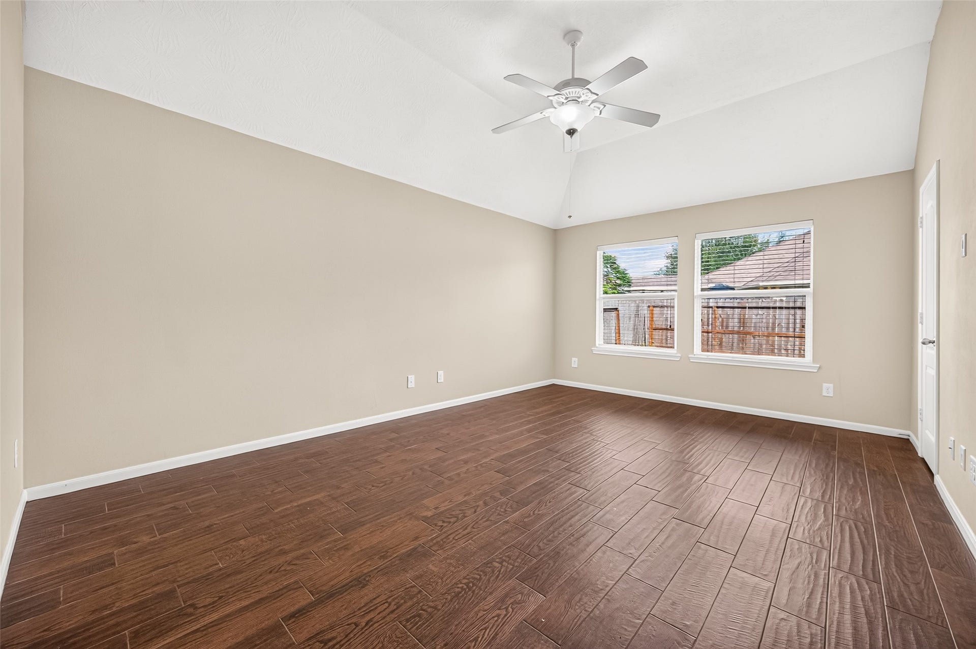 9307 Russeff Field Lane, Rosenberg, TX 77469 Primary bedroom featuring a vaulted ceiling, ceiling fan, wood-look flooring, and windows overlooking the backyard.