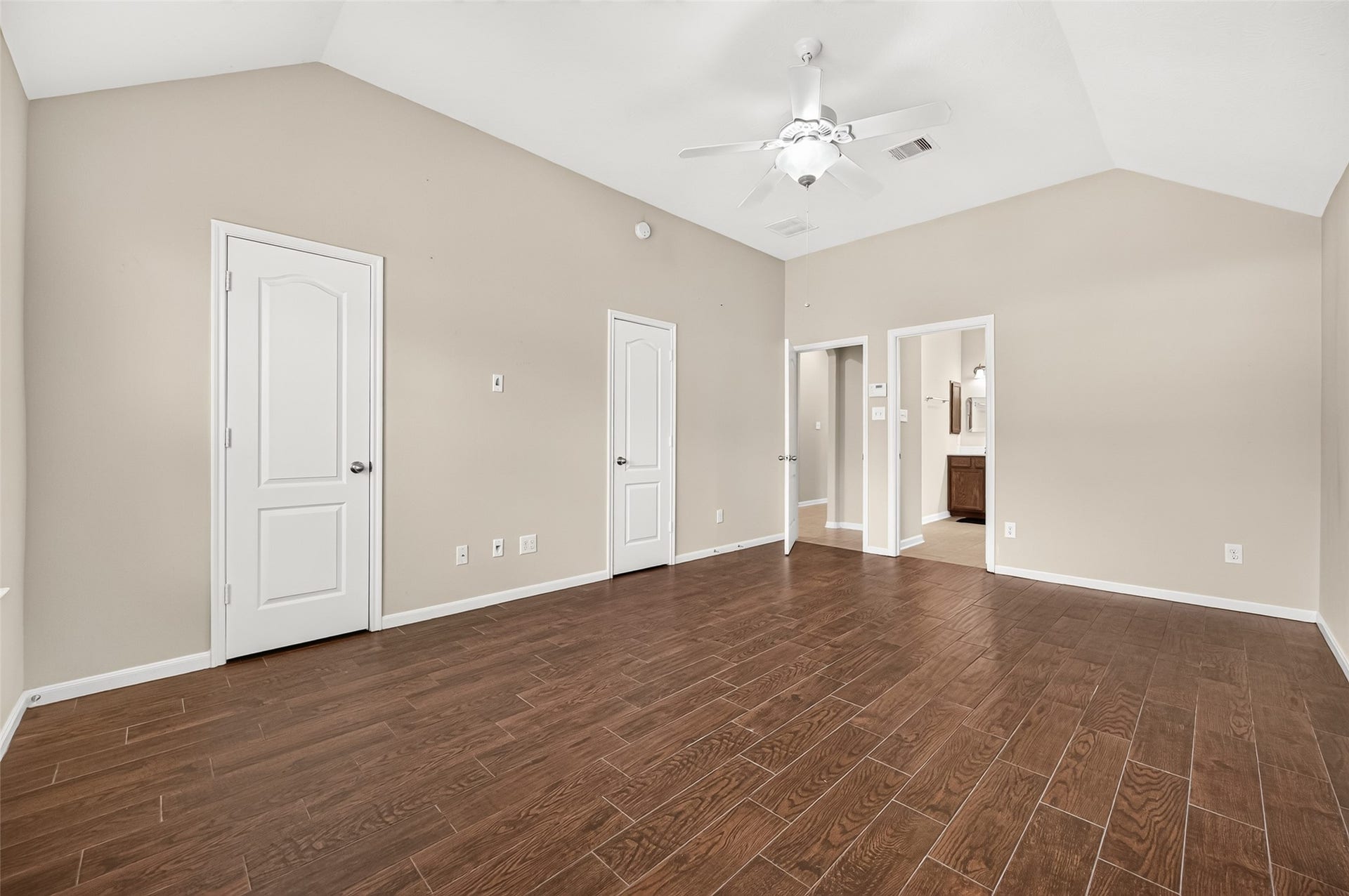 9307 Russeff Field Lane, Rosenberg, TX 77469 Primary bedroom featuring a vaulted ceiling, ceiling fan, rich wood-look flooring, and access to the adjoining bathroom.