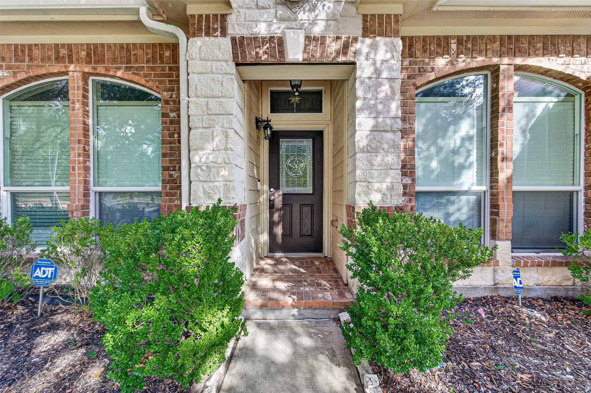 9307 Russeff Field Lane, Rosenberg, TX 77469 Welcoming front entrance featuring brick detailing, an arched entryway, and landscaped surroundings.