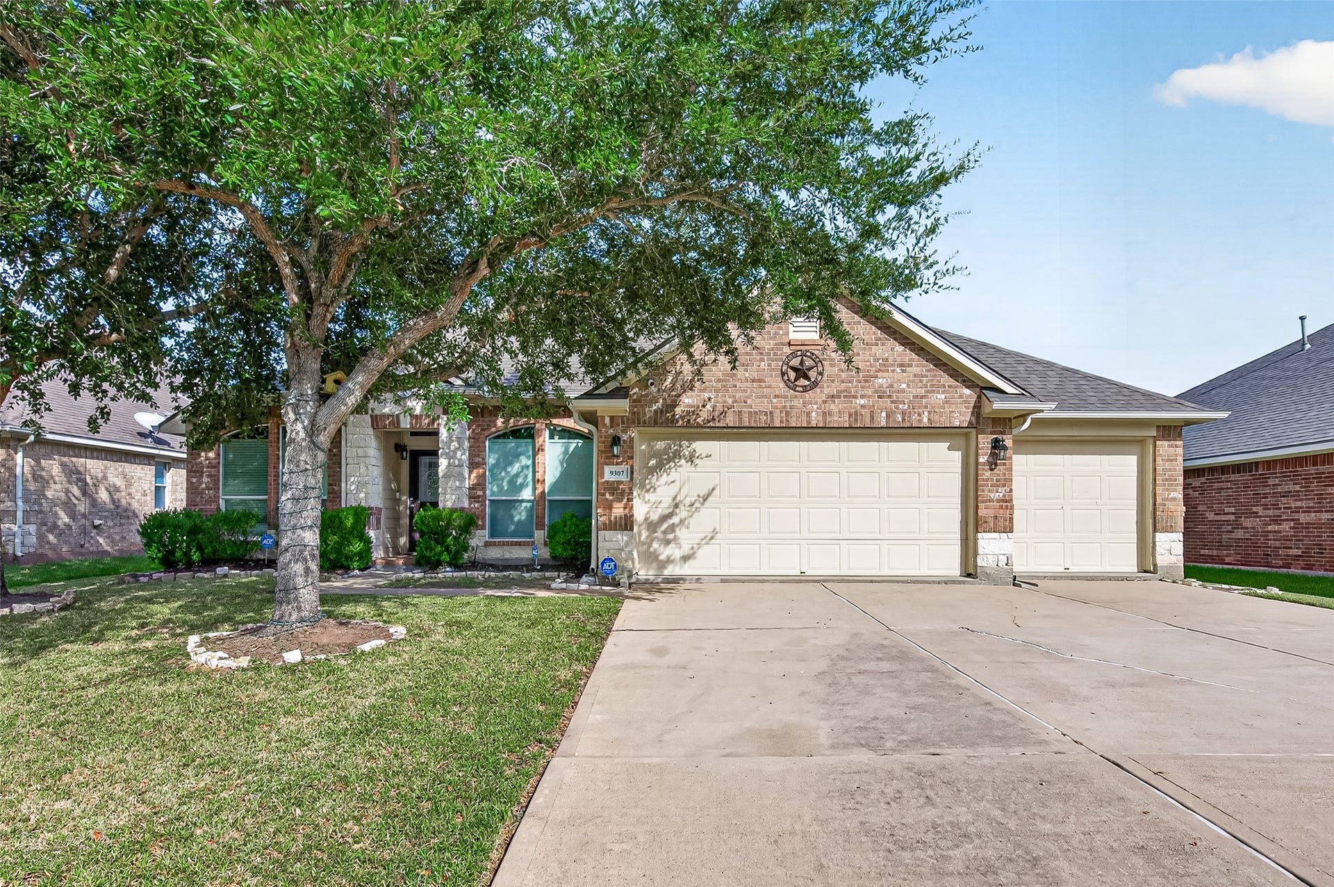9307 Russeff Field Lane, Rosenberg, TX 77469 Front exterior showcasing a brick faade, mature trees, a spacious driveway, and an attached two-car garage.