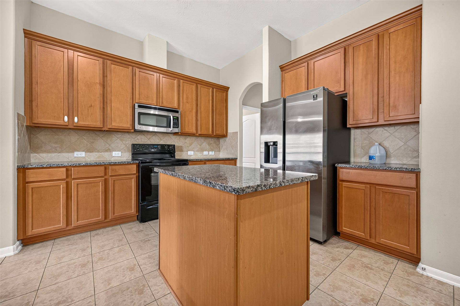 9307 Russeff Field Lane, Rosenberg, TX 77469 Kitchen featuring a center island, generous counter space, wood cabinetry, and tile flooring.
