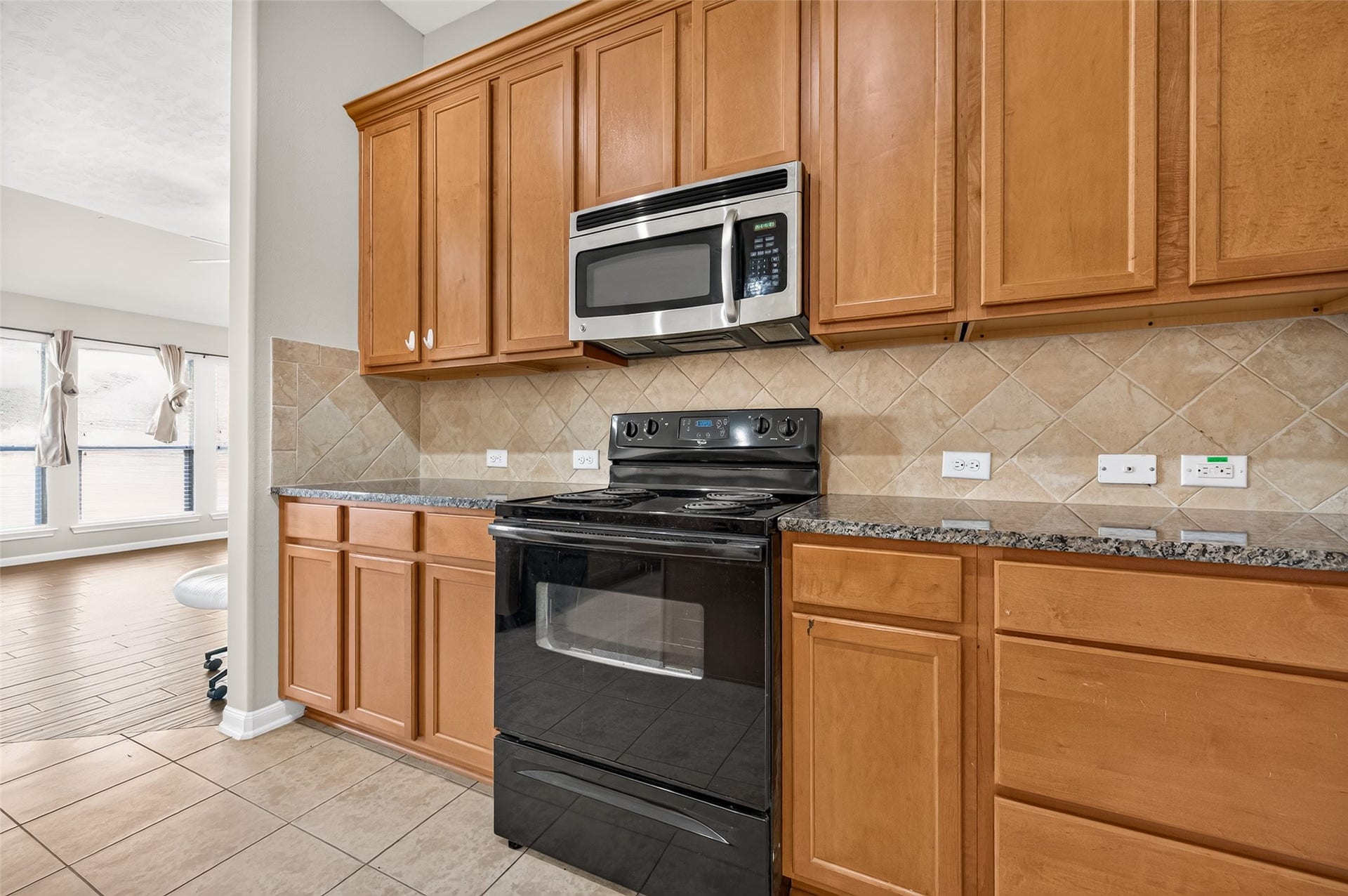 9307 Russeff Field Lane, Rosenberg, TX 77469 Kitchen featuring wood cabinetry, dark countertops, a tile backsplash, and ample workspace.