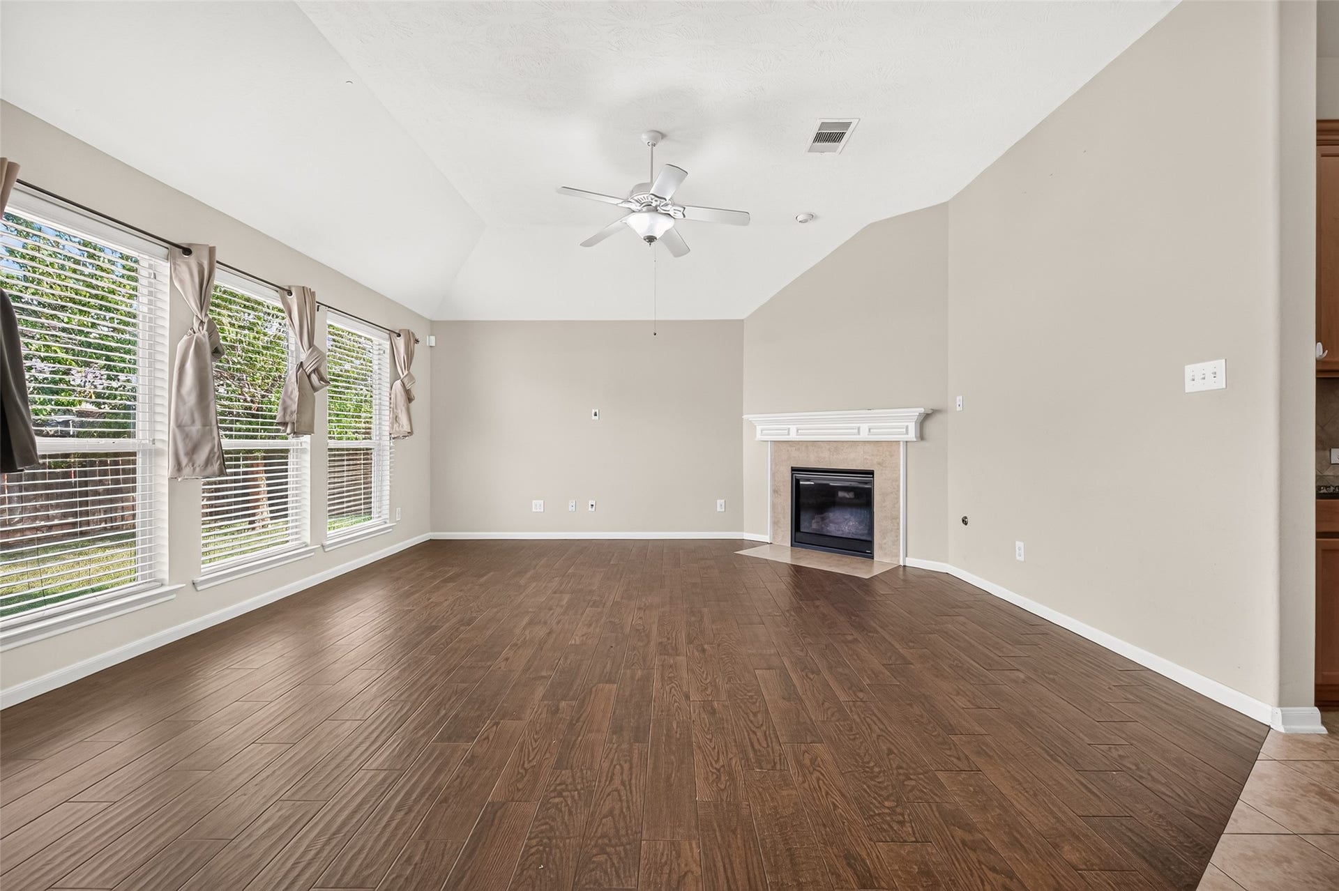 9307 Russeff Field Lane, Rosenberg, TX 77469 Spacious living room featuring a vaulted ceiling, multiple windows, wood-look flooring, and a fireplace.