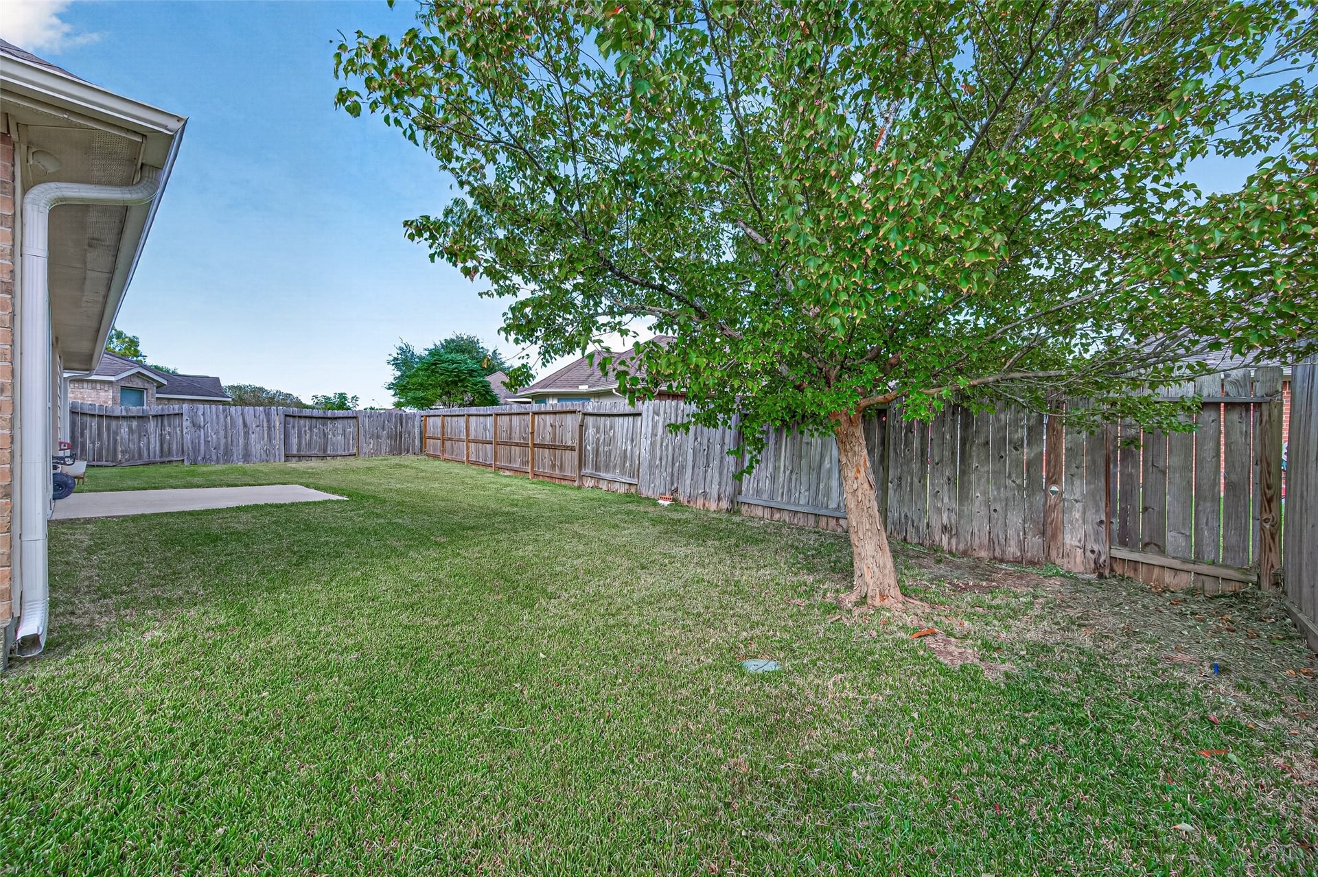 9307 Russeff Field Lane, Rosenberg, TX 77469 Rear exterior view showcasing the covered patio, brick exterior, and expansive grassy backyard.