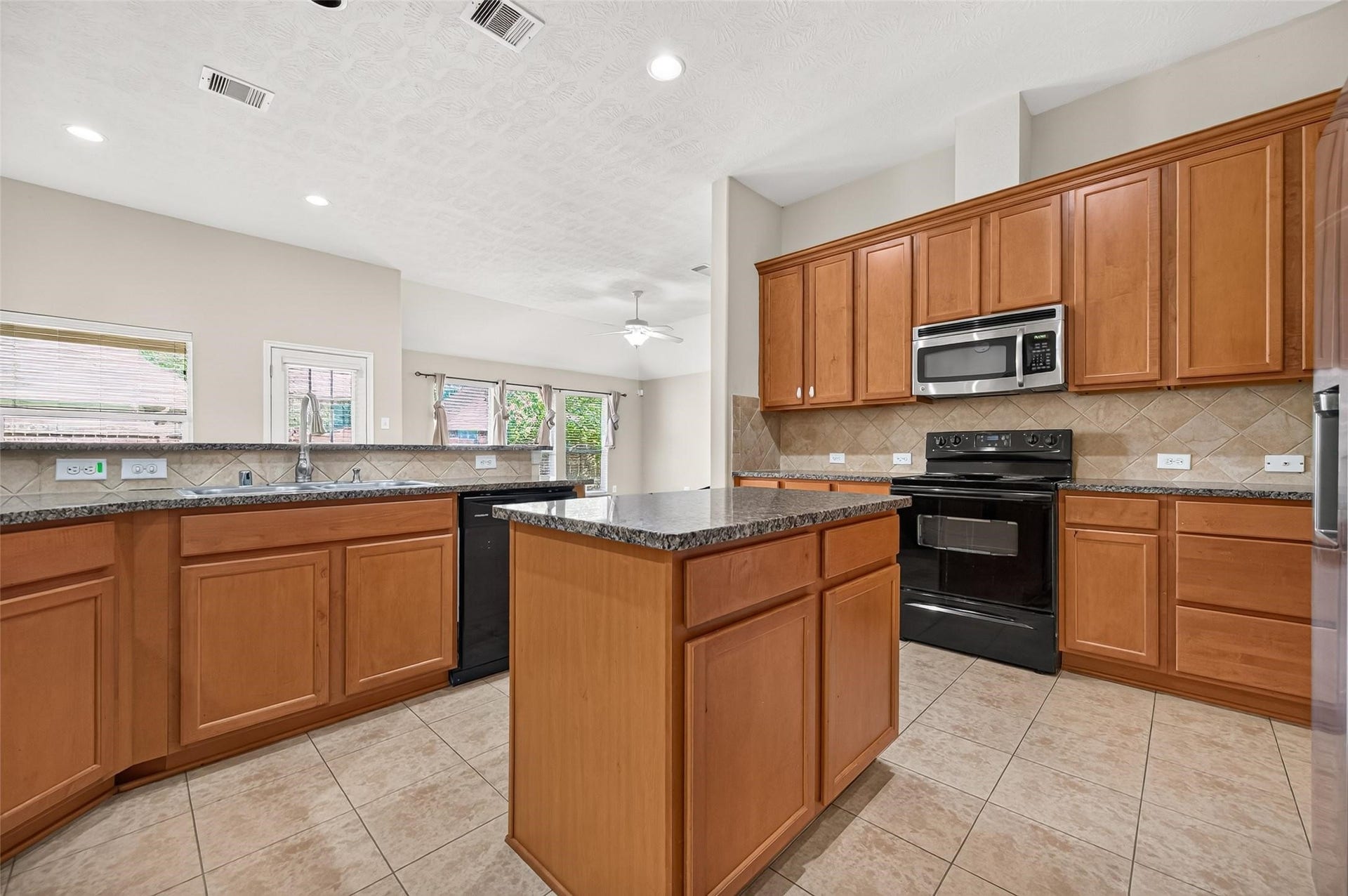 9307 Russeff Field Lane, Rosenberg, TX 77469 Open-concept kitchen featuring warm wood cabinetry, generous counter space, and a center island.